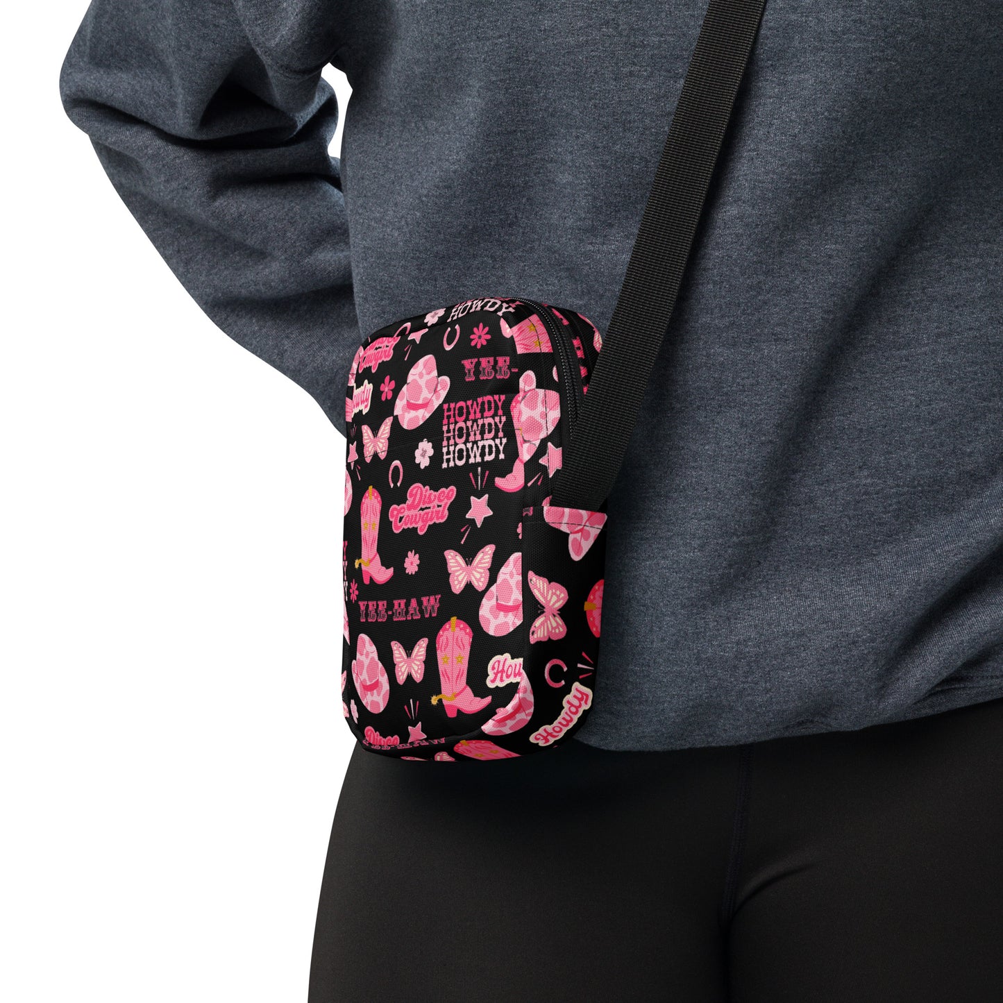 Image: Disco Cowgirl Canvas Crossbody Bag. This small black sling bag features a western glam hot pink pattern of cowgirl boots, cowgirl hats, butterflies and horseshoes. The pattern reads Disco Cowgirl, Yee-Haw and Howdy. The perfect mini backpack for bachelorette parties, gifts for teens or tweens, or trips to the state fair, by jaecrece