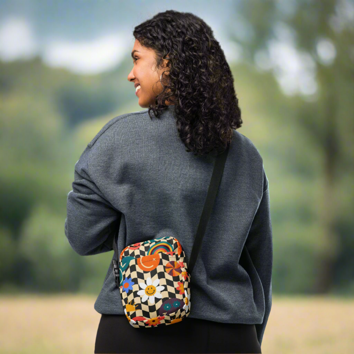 Smiley Face Checkerboard Utility Crossbody Bag. This cute small canvas carryall is eco friendly, and features a black and khaki checkerboard background, with smiley face, rainbow and daisy graphics. It is perfect for hiking, vacations and festivals, and can be worn across the chest, or on the hips/ waist. By jaecrece.com