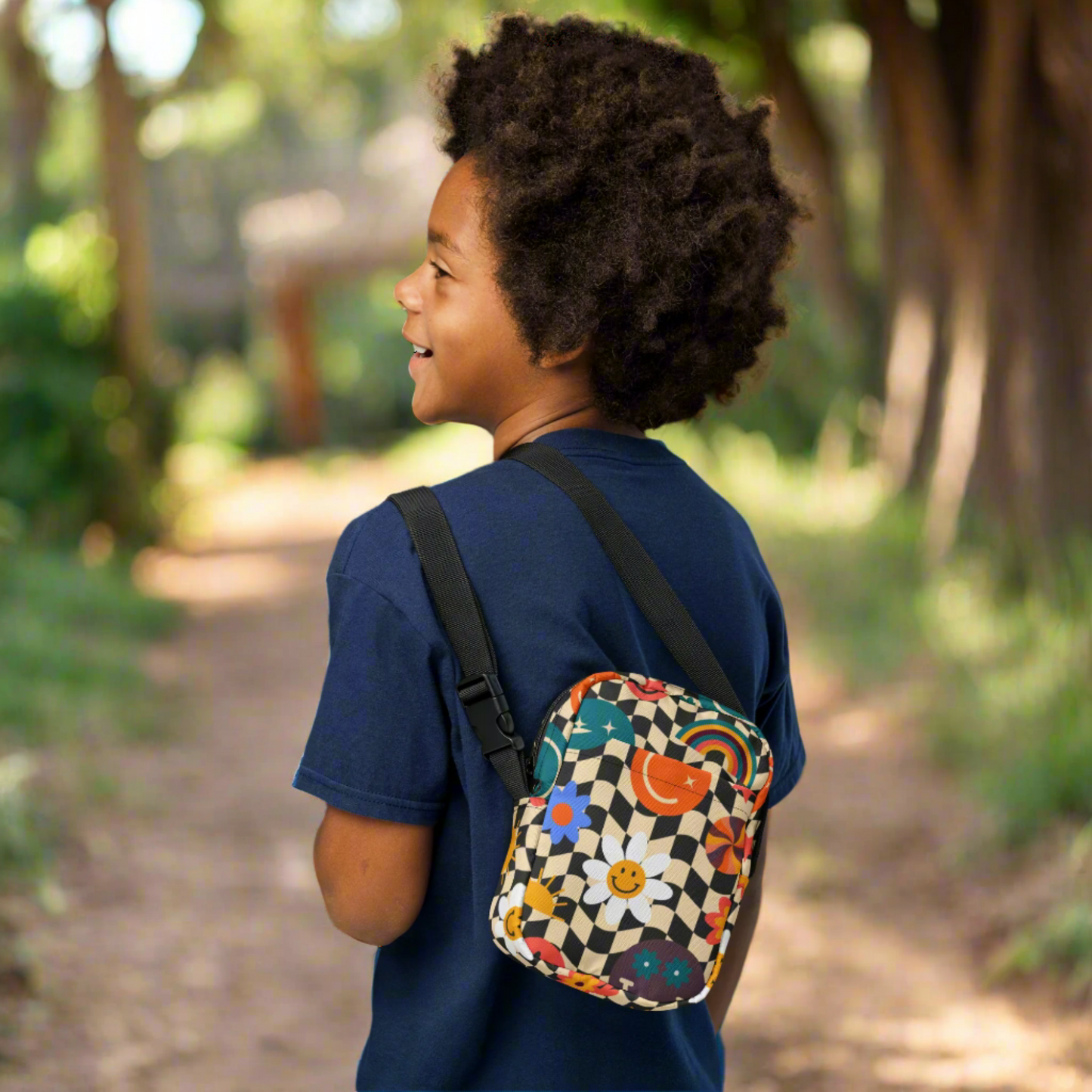 Smiley Face Checkerboard Utility Crossbody Bag. This cute small canvas carryall is eco friendly, and features a black and khaki checkerboard background, with smiley face, rainbow and daisy graphics. It is perfect for hiking, vacations and festivals, and can be worn across the chest, or on the hips/ waist. By jaecrece.com
