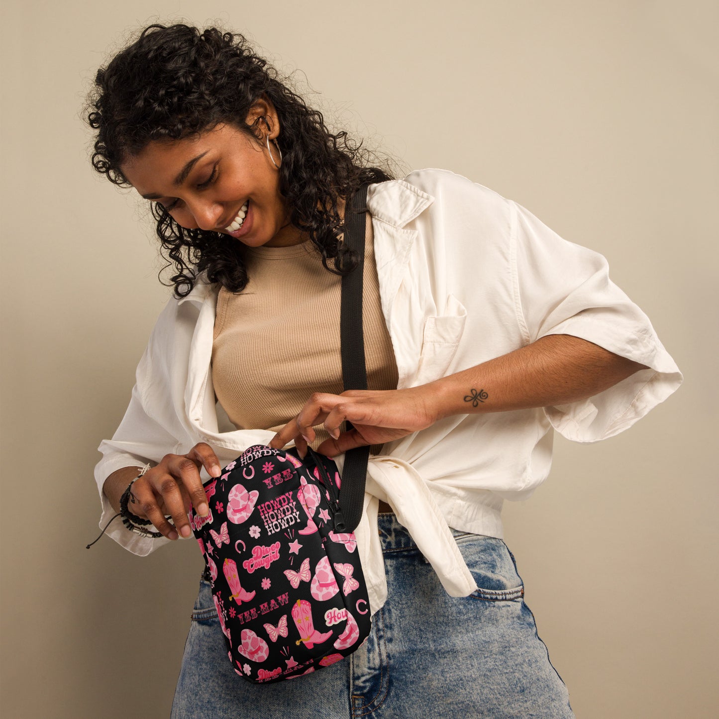 Image: Disco Cowgirl Canvas Crossbody Bag. This small black sling bag features a western glam hot pink pattern of cowgirl boots, cowgirl hats, butterflies and horseshoes. The pattern reads Disco Cowgirl, Yee-Haw and Howdy. The perfect mini backpack for bachelorette parties, gifts for teens or tweens, or trips to the state fair, by jaecrece