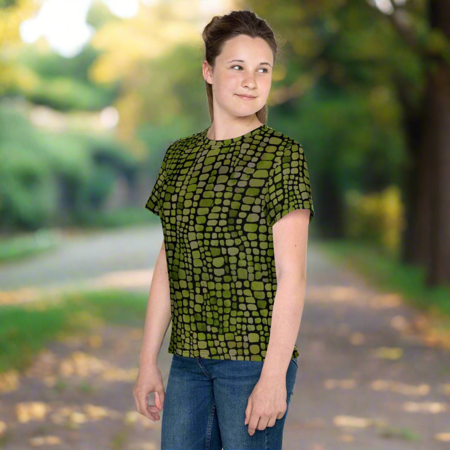 Youth green scale t-shirt in sizes 8–20, designed with a realistic reptile pattern for kids who enjoy imaginative play. Ideal for dressing up as a lizard, snake, or dinosaur, or wearing as a fun everyday look. This all-over print tee is breathable, comfortable, and ready for summer fun, themed birthday parties, or wild outdoor adventures. A fierce addition to any young animal lover’s closet.