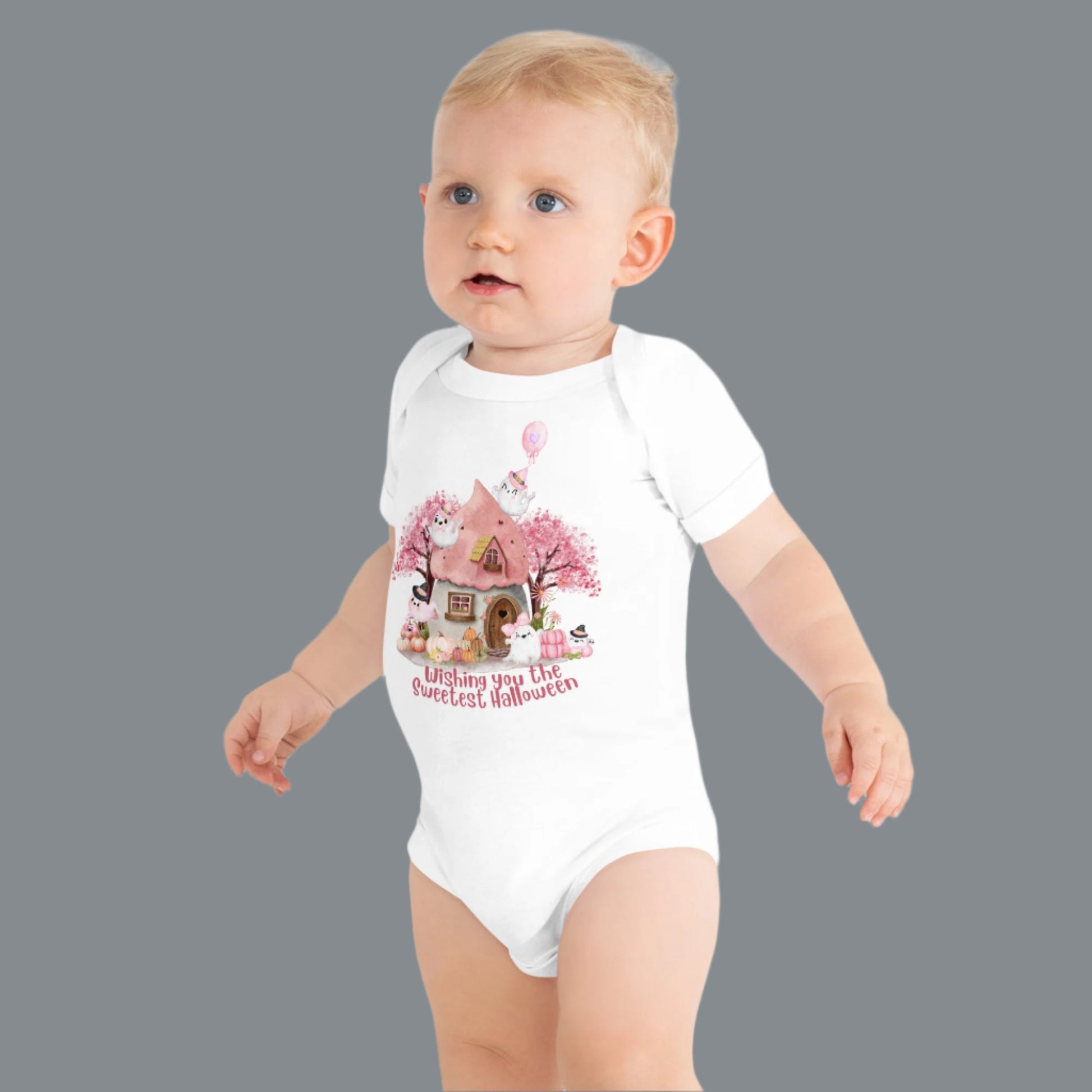 Image: A charming Halloween baby outfit for little girls, this pink onesie showcases a fairy tale cottage surrounded by smiling pumpkins and ghosts. Ideal for newborn photo shoots, October baby showers, and toddler Halloween fashion, this soft and stylish one piece is a customer favorite, by jaecrece.