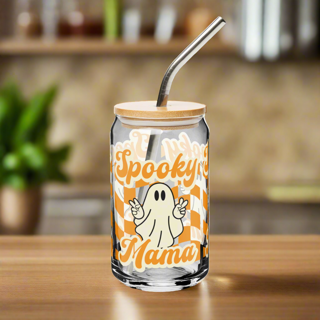Cute Ghost Halloween Fall 16 oz Sipper Glass Funny Halloween Gift for Mom Spooky Mama Halloween Glass Coffee Cup, featuring a orange checkerboard design with a white ghost giving the peace sign and the text Spooky Mama in orange and white cursive bubble font by jaecrece.com