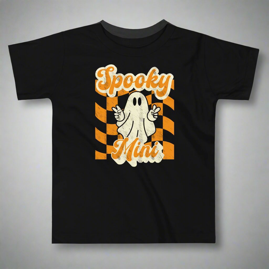 Spooky Mini Halloween Toddler Shirt, featuring a orange checkerboard pattern with a cute ghost graphic. The text reads Spooky Mini, by jaecrece