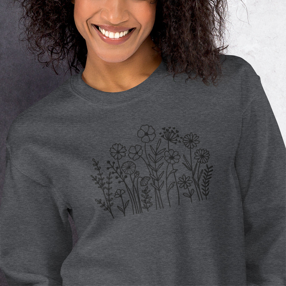 Image: A cozy dark grey sweatshirt with delicate black wildflower embroidery across the chest, showcasing a minimalist yet elegant botanical design. The soft fabric drapes effortlessly, offering comfort for everyday wear. This floral nature crewneck is perfect for layering, adding a subtle floral charm to casual outfits. A thoughtful gift for plant lovers or those who appreciate nature-inspired fashion, by jaecrece.