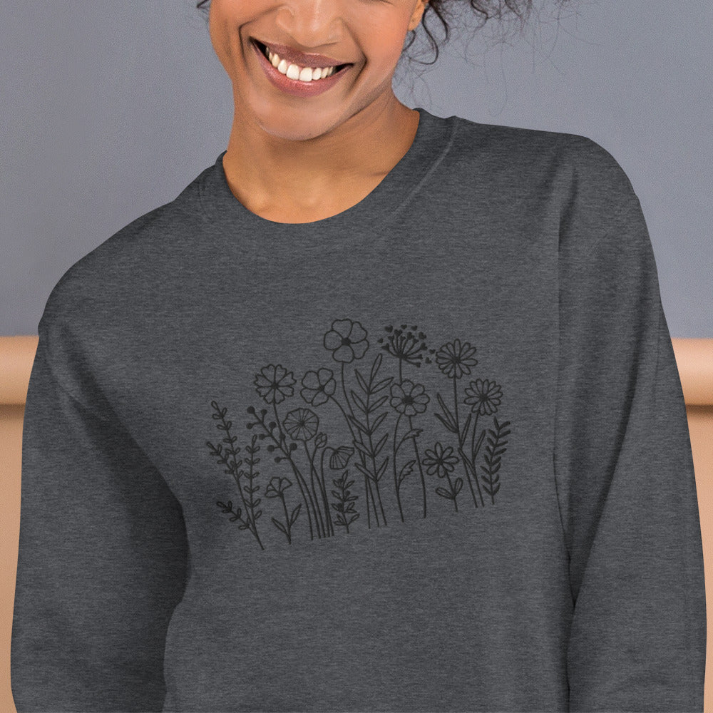 Image: A cozy dark grey sweatshirt with delicate black wildflower embroidery across the chest, showcasing a minimalist yet elegant botanical design. The soft fabric drapes effortlessly, offering comfort for everyday wear. This floral nature crewneck is perfect for layering, adding a subtle floral charm to casual outfits. A thoughtful gift for plant lovers or those who appreciate nature-inspired fashion, by jaecrece.