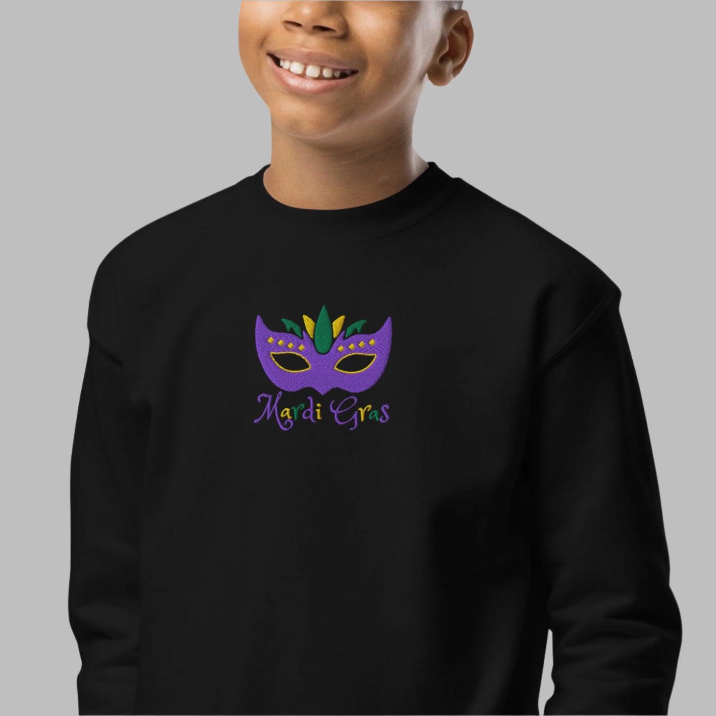 Celebrate the season in this Mardi Gras embroidered youth sweatshirt, available in XS to XL. Featuring a detailed purple, green, and gold carnival mask and bold “Mardi Gras” text, this cozy top is perfect for school events, parades, or family gatherings. Coordinates with adult sizes for a family matching Mardi Gras outfit. A festive choice for kids holiday clothing and New Orleans Mardi Gras fashion lovers.