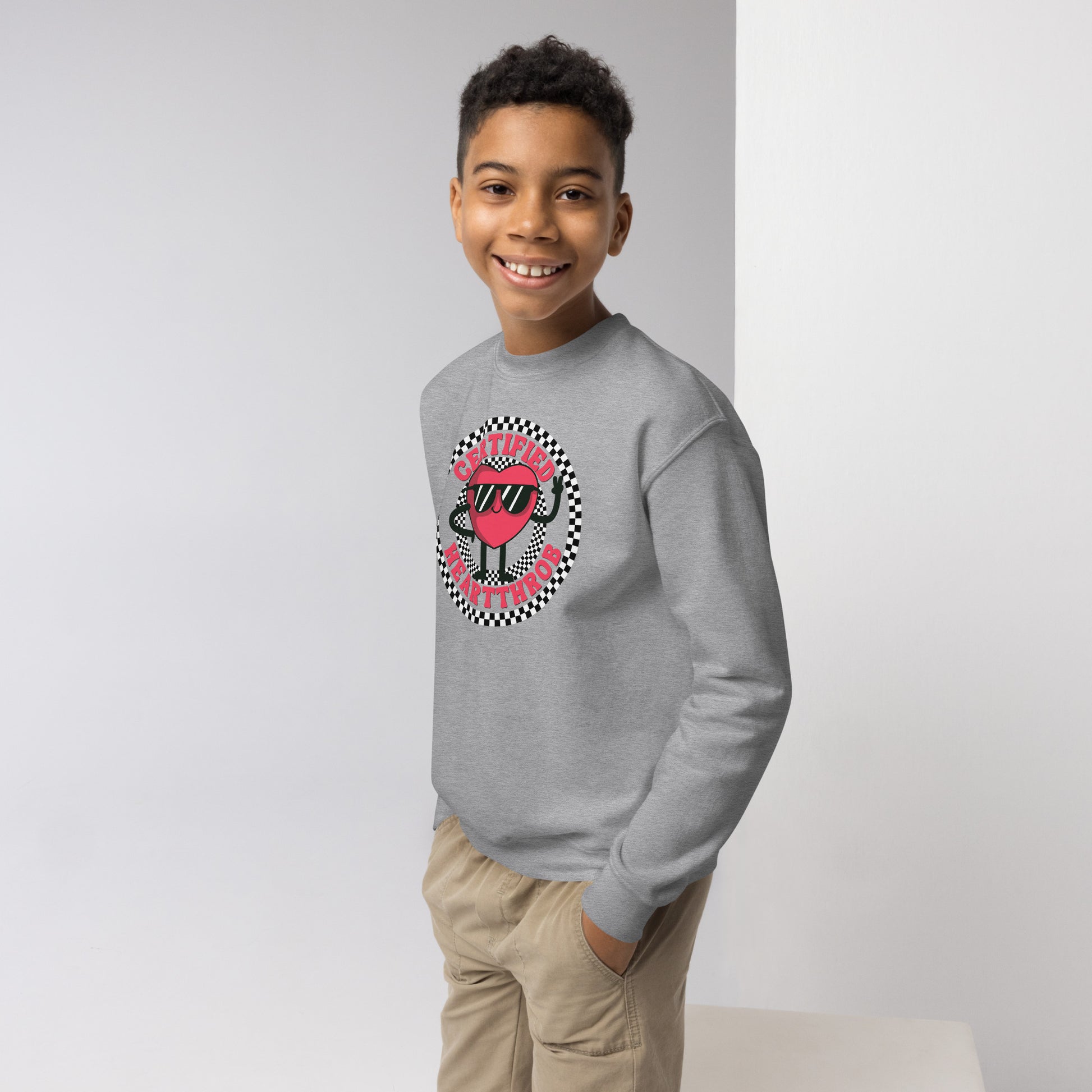 Image: Certified Heartthrob Sweatshirt. This Valentines Day sweater for boys or girls is available in white or gray. It features a checker pattern ring, with a cartoon heart man wearing sunglasses, with the text Certified Heartthrob, by jaecrece