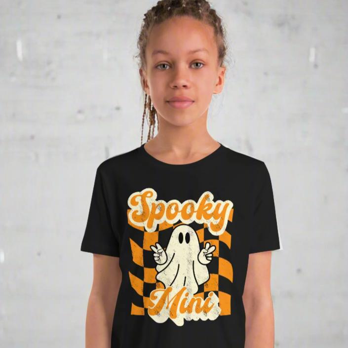 Spooky Mini Unisex Youth shirt, for girls and boys, featuring an orange checkerboard pattern with a cute ghost and the text Spooky Mini, by jaecrece