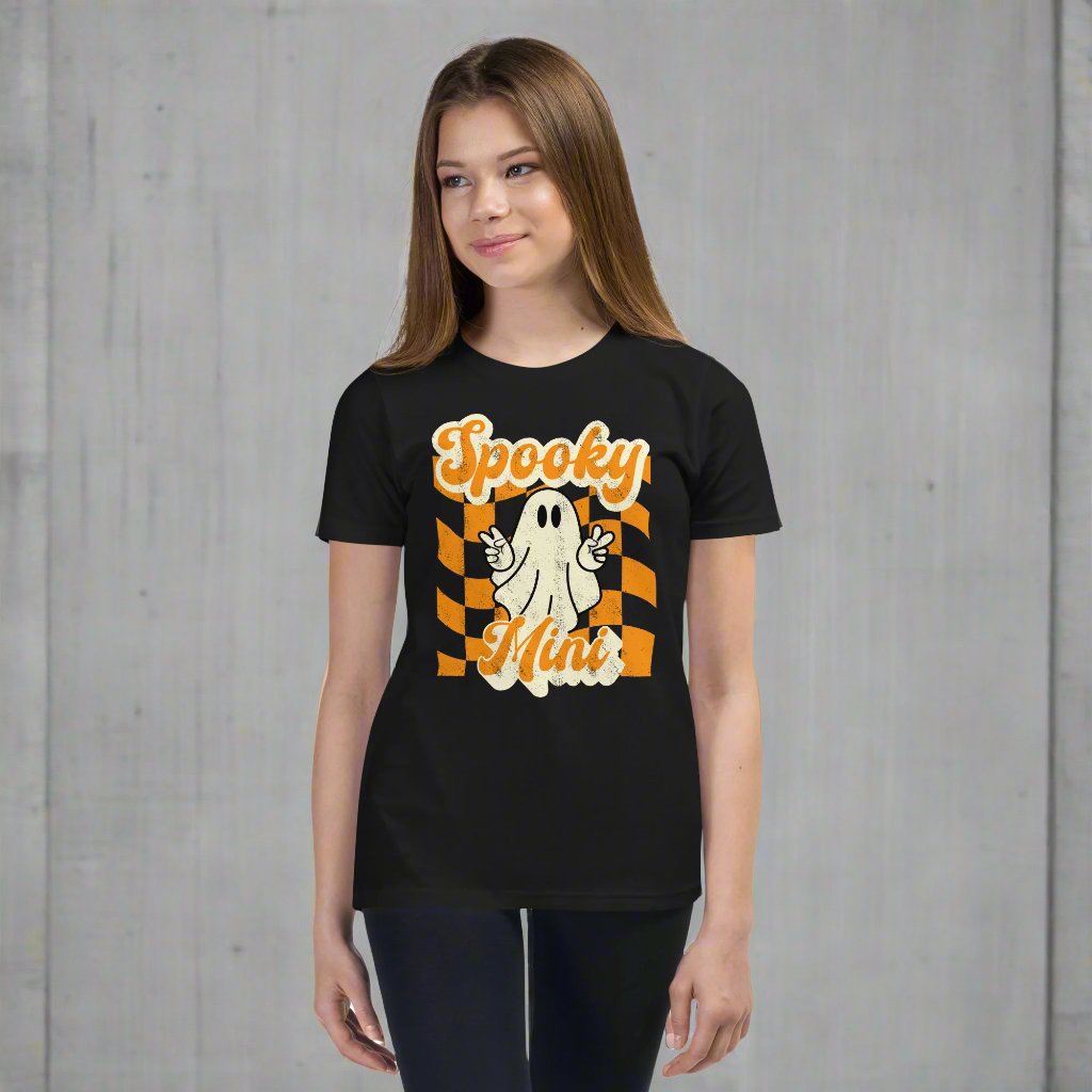 Spooky Mini Unisex Youth shirt, for girls and boys, featuring an orange checkerboard pattern with a cute ghost and the text Spooky Mini, by jaecrece