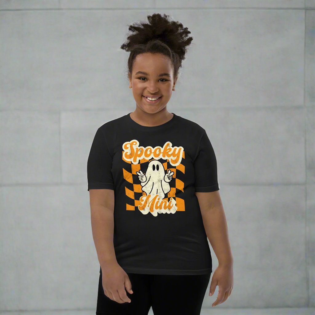 Spooky Mini Unisex Youth shirt, for girls and boys, featuring an orange checkerboard pattern with a cute ghost and the text Spooky Mini, by jaecrece