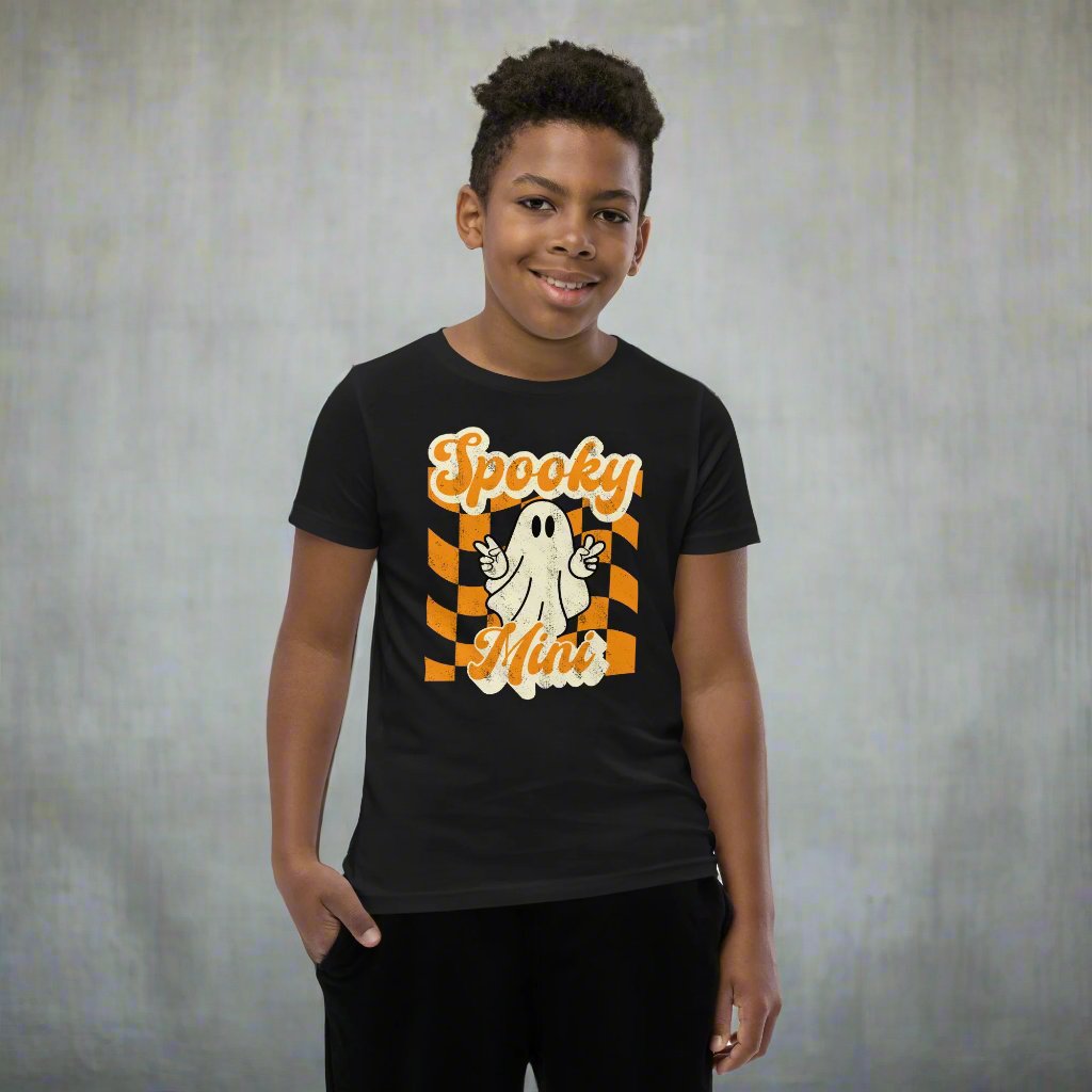 Spooky Mini Unisex Youth shirt, for girls and boys, featuring an orange checkerboard pattern with a cute ghost and the text Spooky Mini, by jaecrece