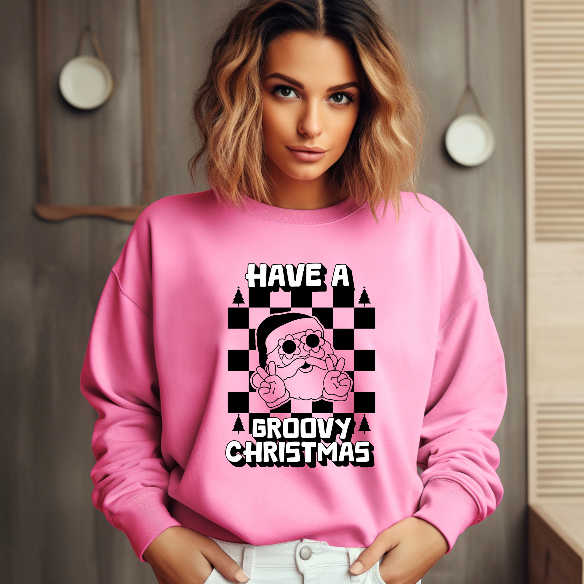 Image: retro Santa christmas sweatshirt available in pink and bright green. The text reads Have a groovy Christmas, with a black checkerboard background, and a vintage Santa wearing daisy sunglasses and giving the peace sign. The perfect gift for those who love a funky vintage aesthetic, by jaecrece