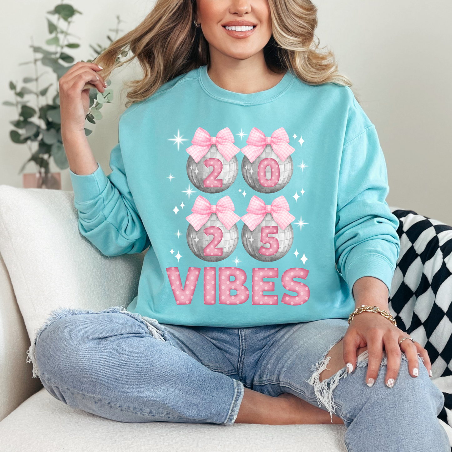 Image: Happy New Years Eve Sweatshirt is available in four colors- denim, graphite, white and chalky mint. There are 4 silver disco balls, with  pink gingham ribbon and 2025 on each. VIBES is in pink coquette polka dot block letters. by jaecrece