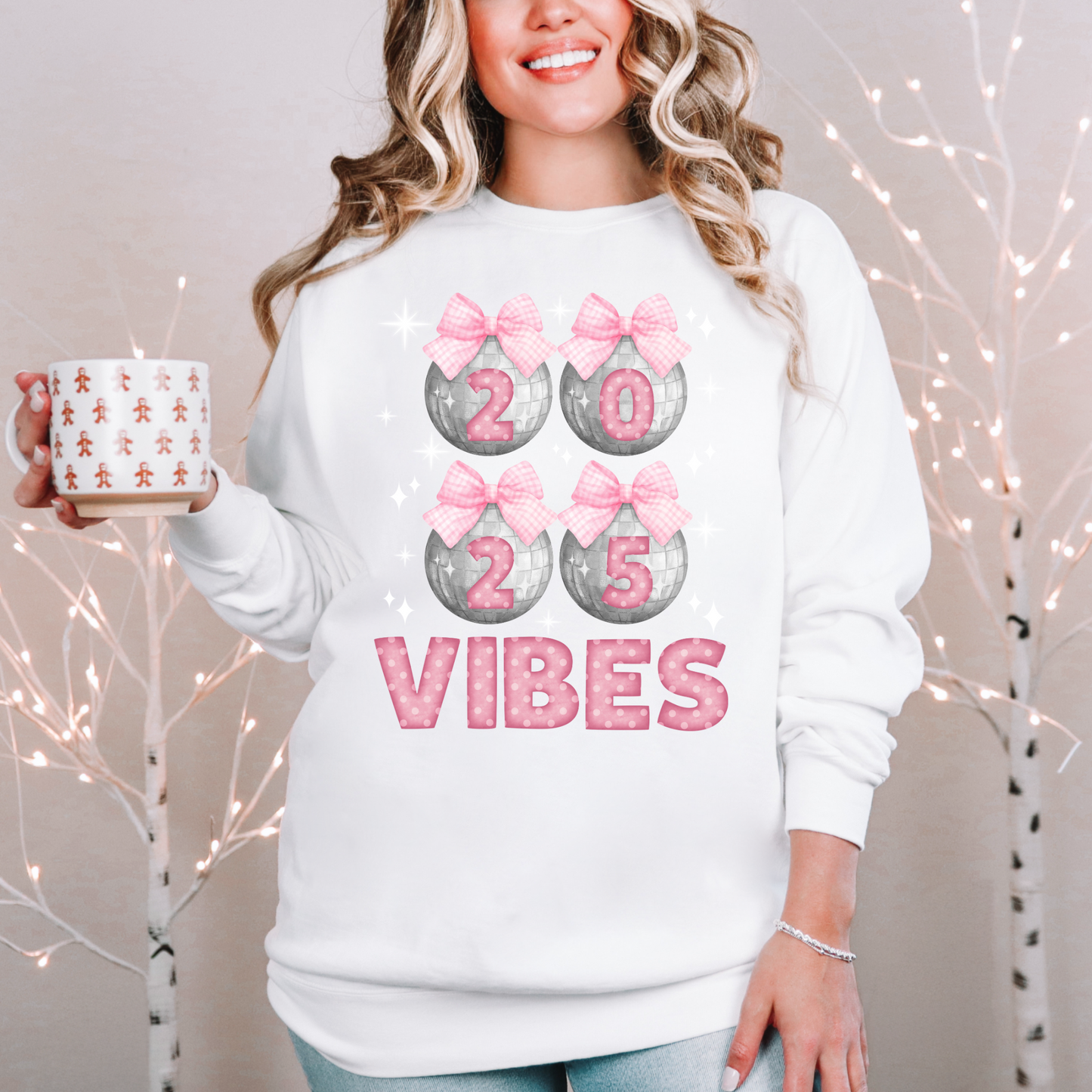 Image: Happy New Years Eve Sweatshirt is available in four colors- denim, graphite, white and chalky mint. There are 4 silver disco balls, with  pink gingham ribbon and 2025 on each. VIBES is in pink coquette polka dot block letters. by jaecrece