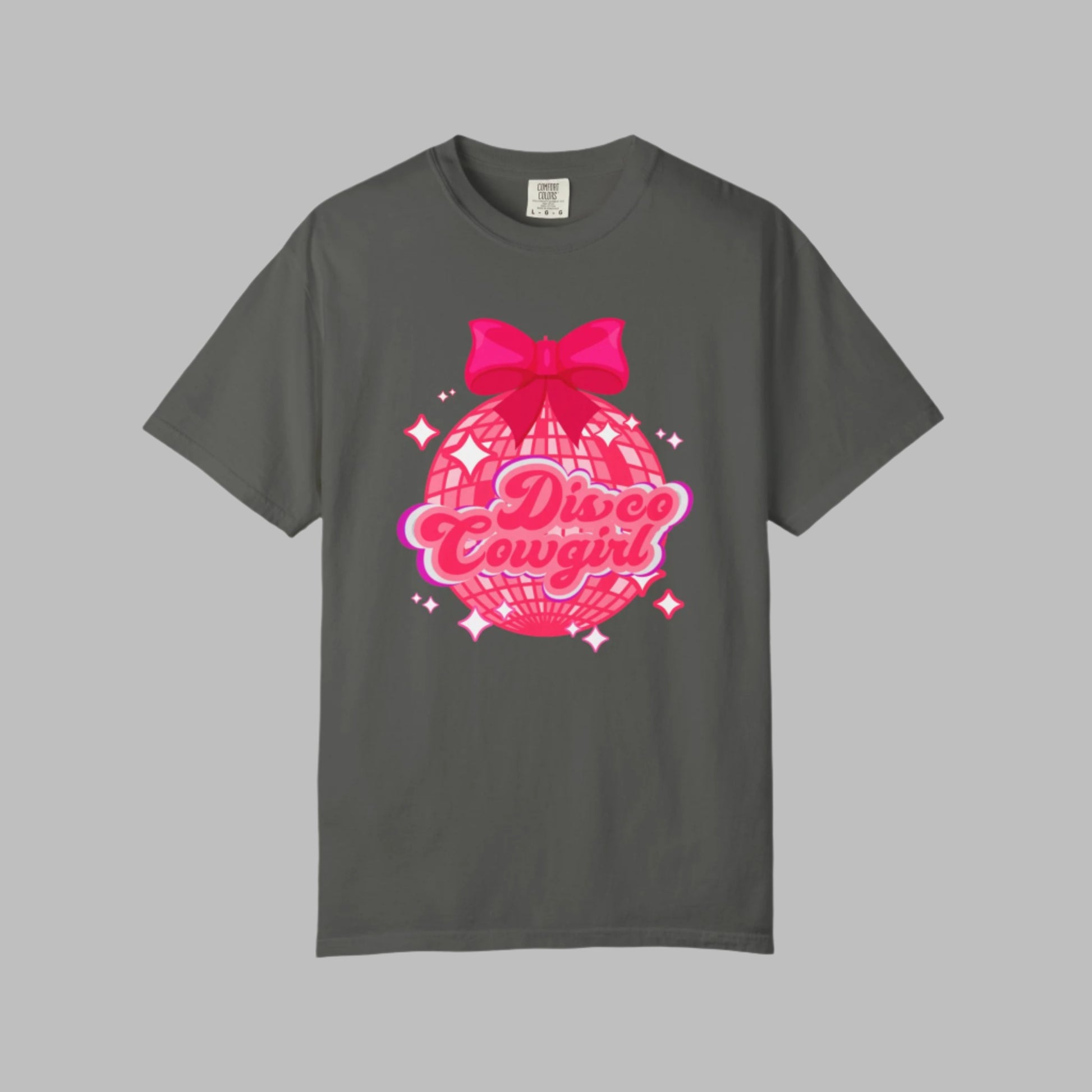 Disco Cowgirl tee for women in Comfort Colors is designed with a glittery pink disco ball, hot pink bow, and bright lettering. Ideal for matching party outfits, this retro western shirt is a cute coquette option for bachelorettes, rodeos, or girls' weekends. Available in S–4XL in multiple neutral shades for a flattering, oversized fit.