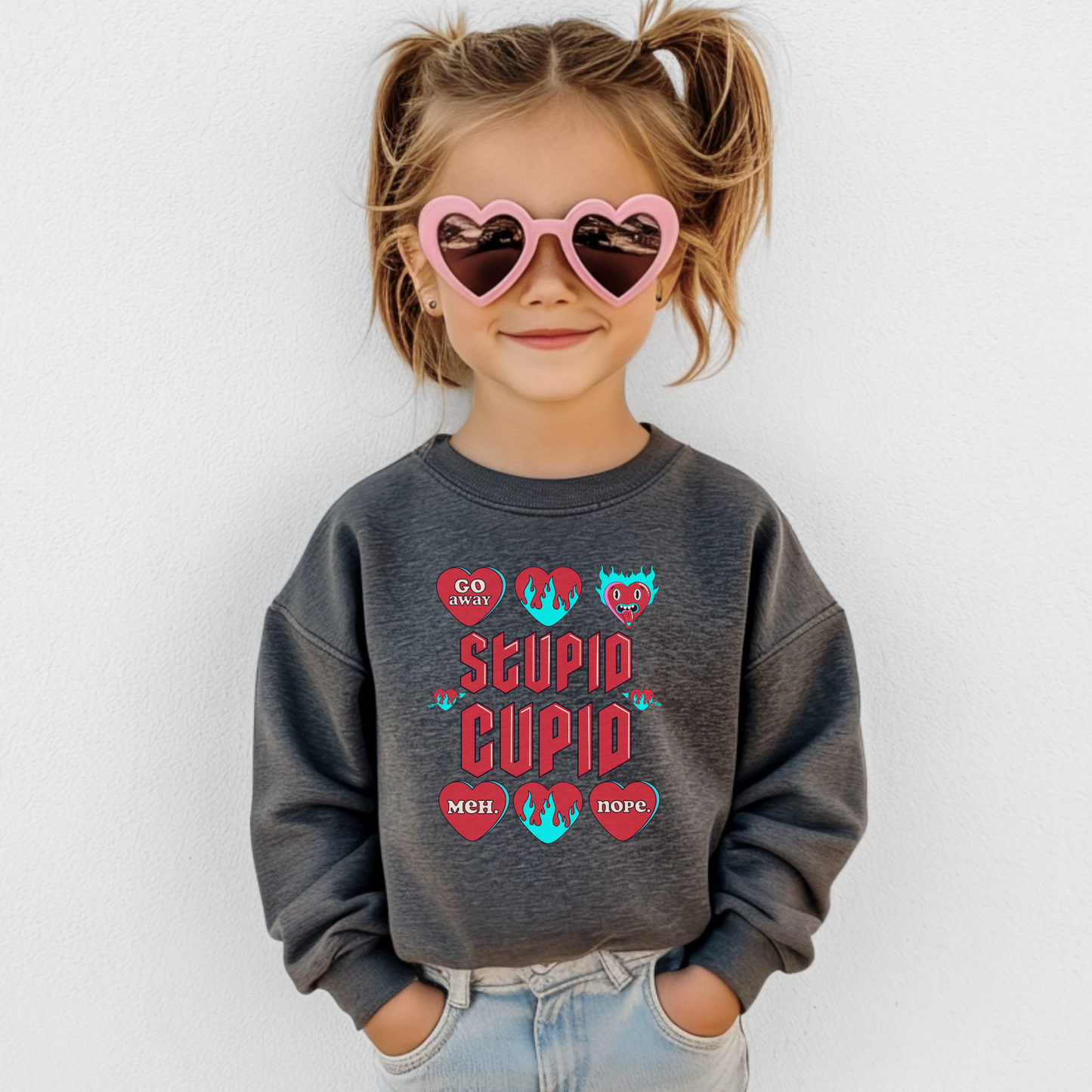 Image: Stupid Cupid Anti Valentines Day T-shirt for Kids. This sweatshirt is for girls and boys with red 90s style text that reads Stupid Cupid, with conversation hearts that are on fire, or say Go Away, Meh, Nope. Great for school party, by jaecrece