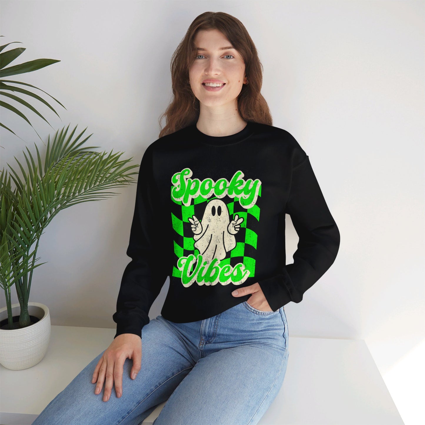 Black Halloween Unisex sweatshirt, featuring a green checkboard pattern, cute ghost giving the peace sign, and the text Spooky vibes, by jaecrece