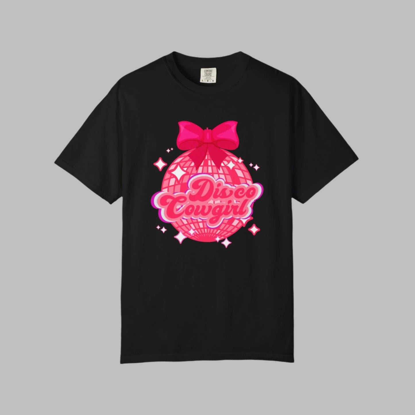 Women's Disco Cowgirl graphic t-shirt features a large disco ball, hot pink coquette bow, and star-speckled background with “Disco Cowgirl” in playful script. This Comfort Colors tee is a top pick for western-themed events, fun bachelorette outings, or cozy Nashville nights. Soft, garment-dyed cotton in sizes S–4XL makes it a cute and comfy must-have.