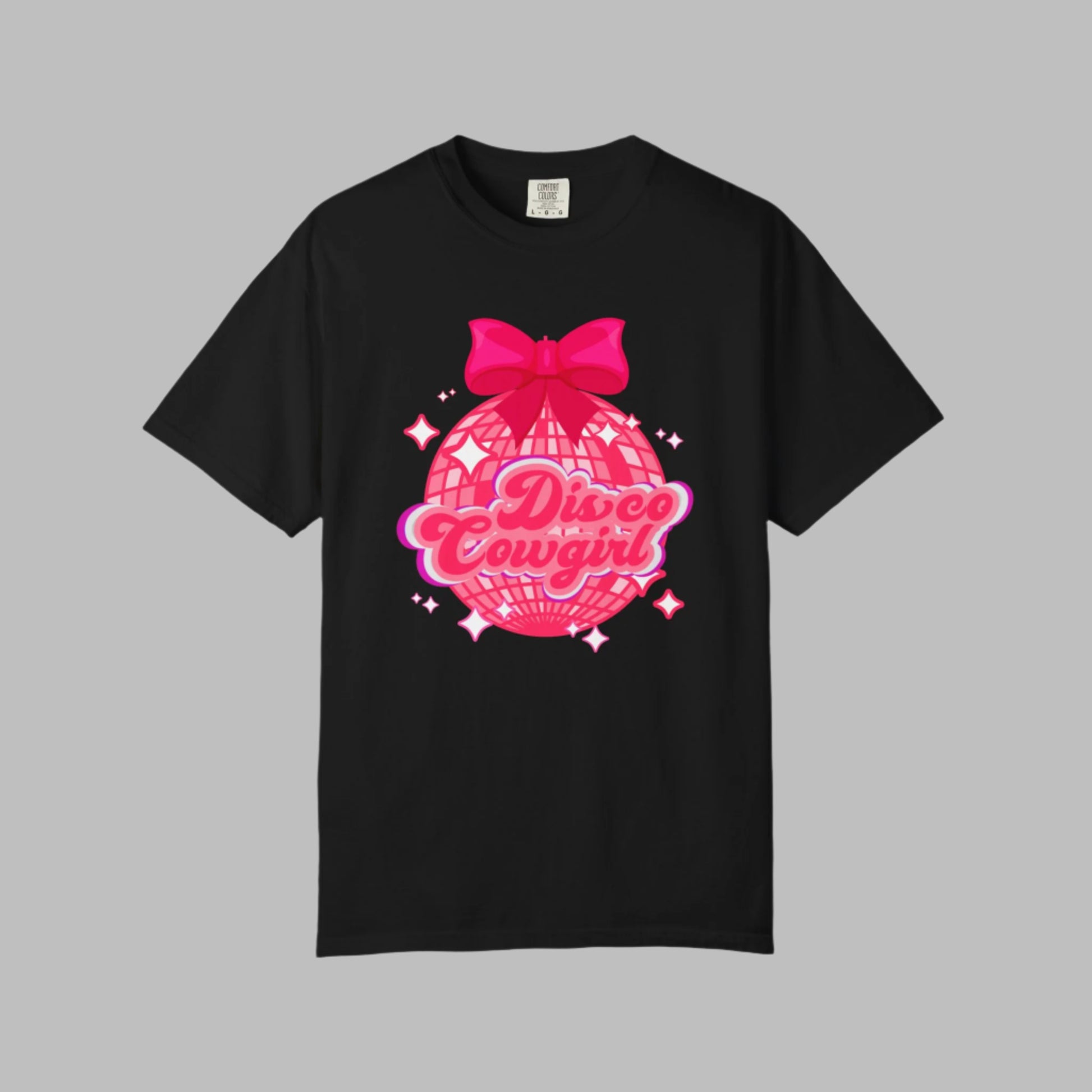 Women's Disco Cowgirl graphic t-shirt features a large disco ball, hot pink coquette bow, and star-speckled background with “Disco Cowgirl” in playful script. This Comfort Colors tee is a top pick for western-themed events, fun bachelorette outings, or cozy Nashville nights. Soft, garment-dyed cotton in sizes S–4XL makes it a cute and comfy must-have.