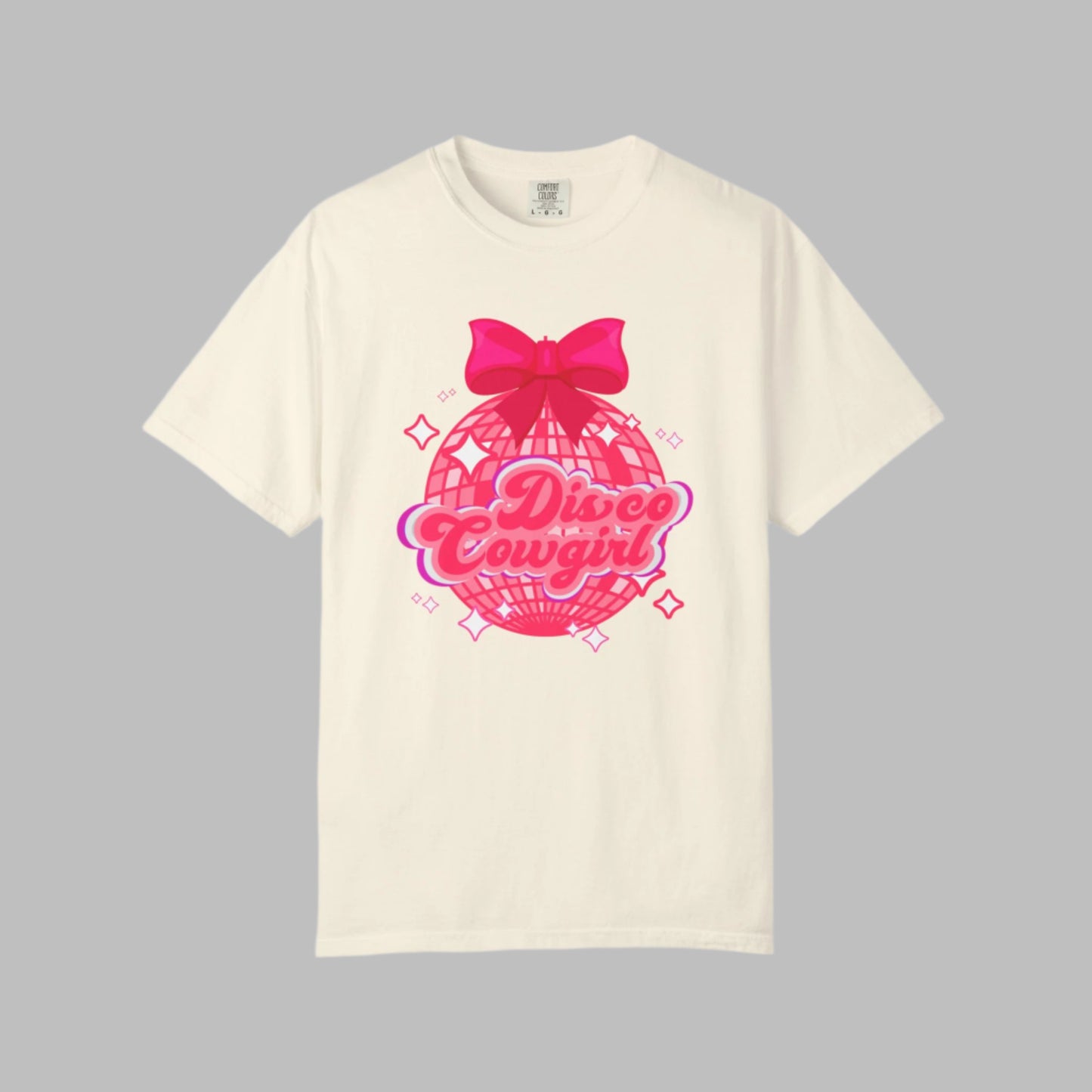 This women's western graphic tee features a pink disco ball with star accents, topped with a cute pink bow and “Disco Cowgirl” in script. A great choice for parties, Nashville trips, or rodeo nights. Comfort Colors 1717 shirt offers a relaxed fit and soft fabric in fun colors. Perfect for boutique-style cowgirl fashion. Sizes S–4XL.

