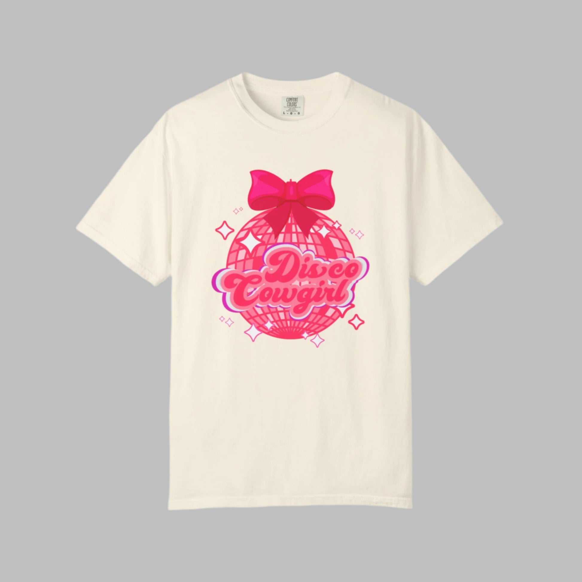 This women's western graphic tee features a pink disco ball with star accents, topped with a cute pink bow and “Disco Cowgirl” in script. A great choice for parties, Nashville trips, or rodeo nights. Comfort Colors 1717 shirt offers a relaxed fit and soft fabric in fun colors. Perfect for boutique-style cowgirl fashion. Sizes S–4XL.


