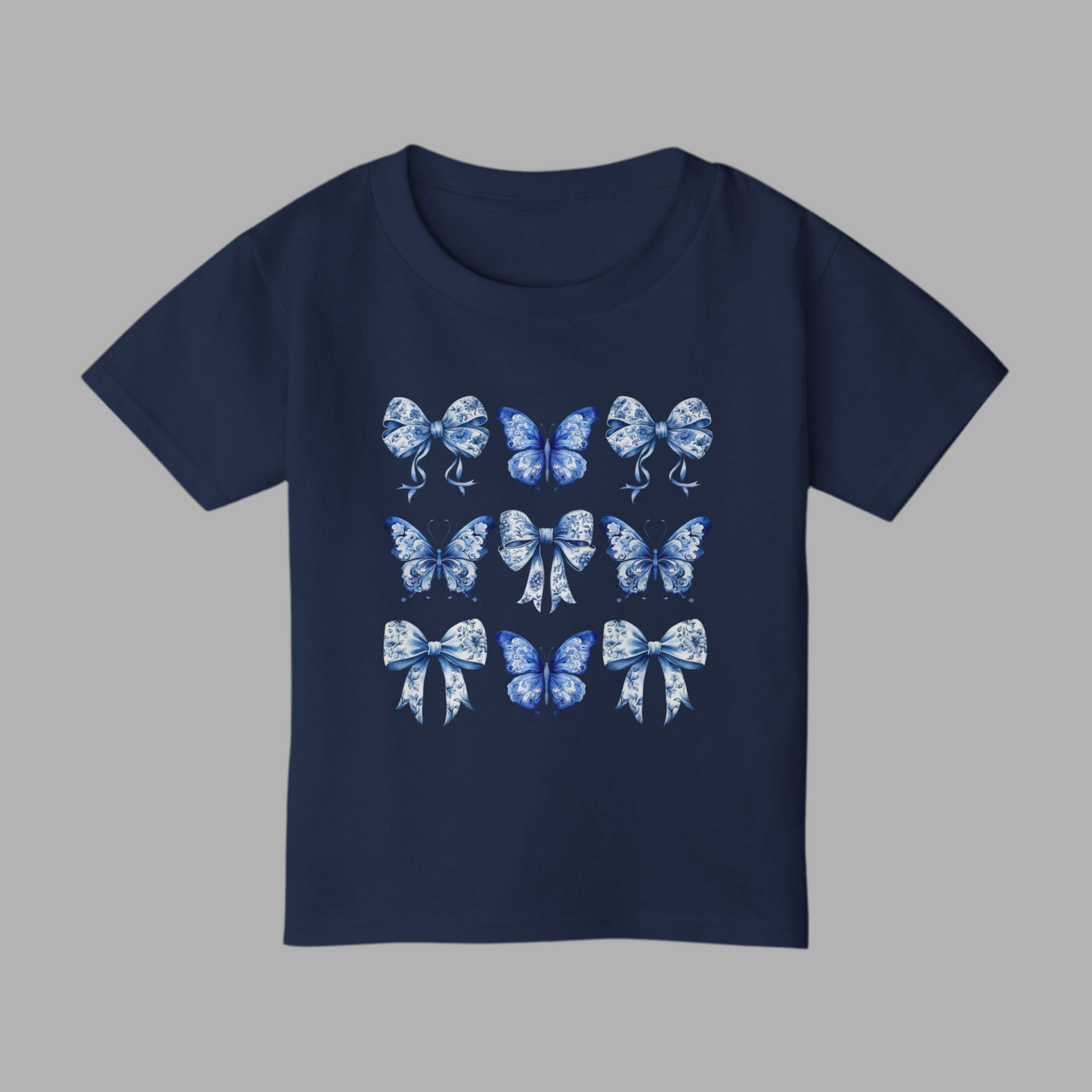 Adorable toddler girl T-shirt in soft cotton showcases a vintage blue toile design with butterflies and bows, channeling the popular Texas coquette and coastal cowgirl aesthetics. This stylish toddler tee is a wardrobe essential for spring outings, western-themed parties, and sibling matching looks. Available in sizes 2T to 6T, it makes an excellent gift for southern sweethearts or beachy boho babies, by jaecrece.