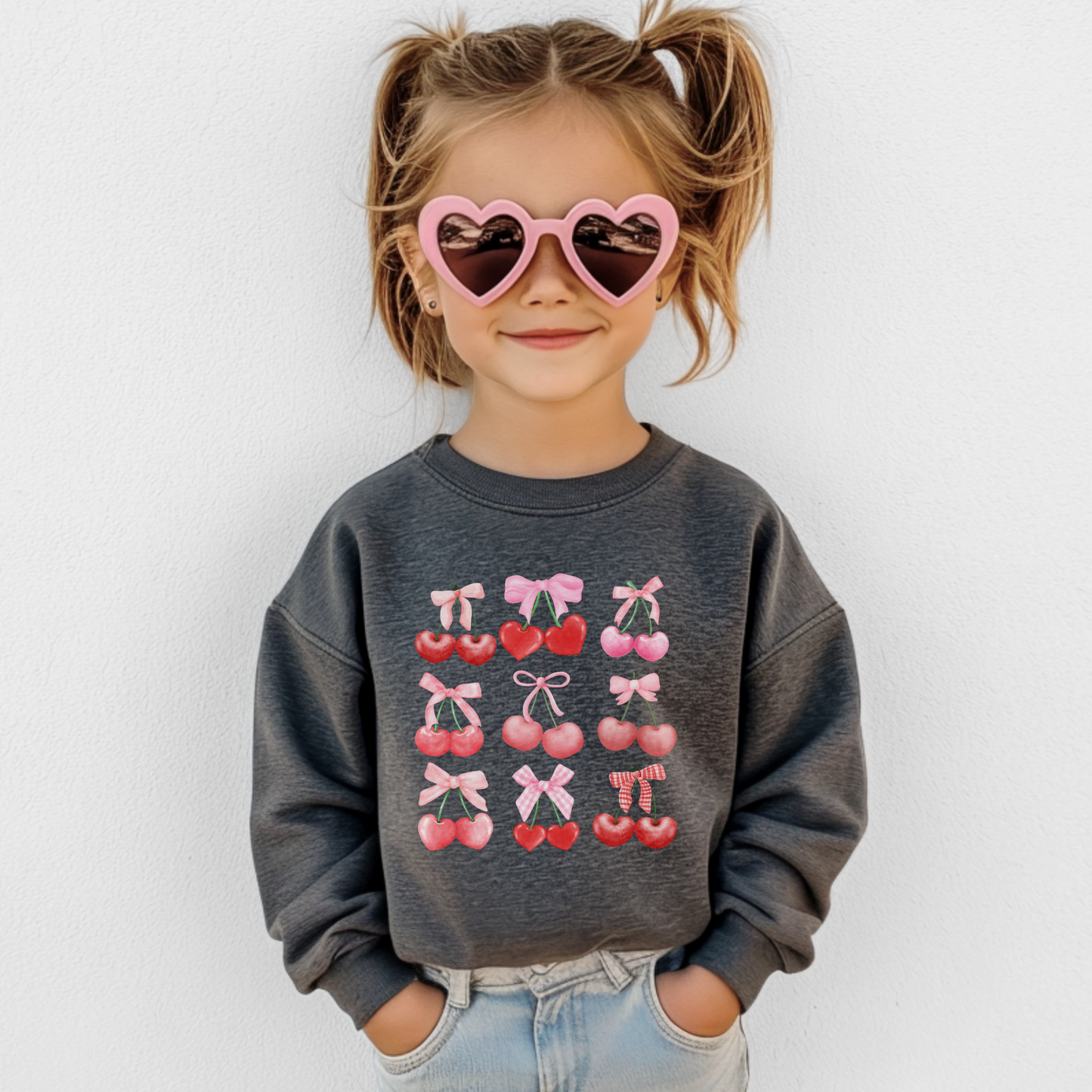 Image: Cherry Bow Girls Sweatshirt, available in Hot pink, White and dark gray. This coquette aesthetic shirt features 9 different cherries with bows, making a large soft girly graphic. Makes a great Valentines gift for toddlers and little girls, by jaecrece