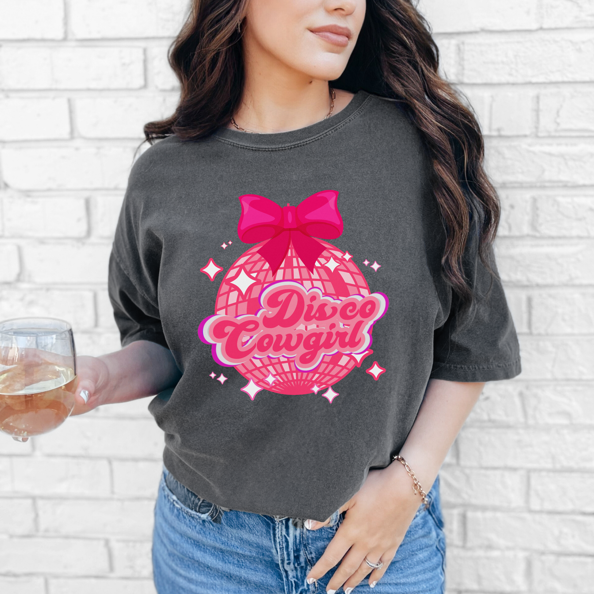 Disco Cowgirl women's tee in Comfort Colors style 1717 features a large pink disco ball, bright hot pink coquette bow, and playful “Disco Cowgirl” script in pink and purple. The scattered stars create a fun, festive look. This soft cotton tee is great for country music events, themed birthdays, and bachelorette parties. Available in four colors and sizes S–4XL.

