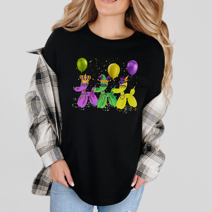 Image: Mardi Gras Balloon Dog Adult Shirt. This New Orleans Carnival tee features three balloons dogs, wearing Mardi Gras masks and hats. They have beads and balloons with confetti, by jaecrece