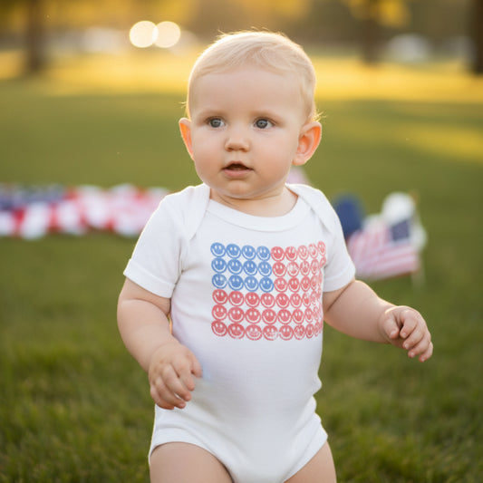 White Bella Canvas infant bodysuit featuring a retro American flag design made from rows of red and blue smiley faces. Soft short sleeve baby onesie designed for comfort and everyday wear. Perfect patriotic outfit for 4th of July celebrations, summer family photos, and holiday events. Made for newborns and infants with easy snap closure for diaper changes. Great baby shower gift and ideal for America 250 themed celebrations and festive seasonal styling.