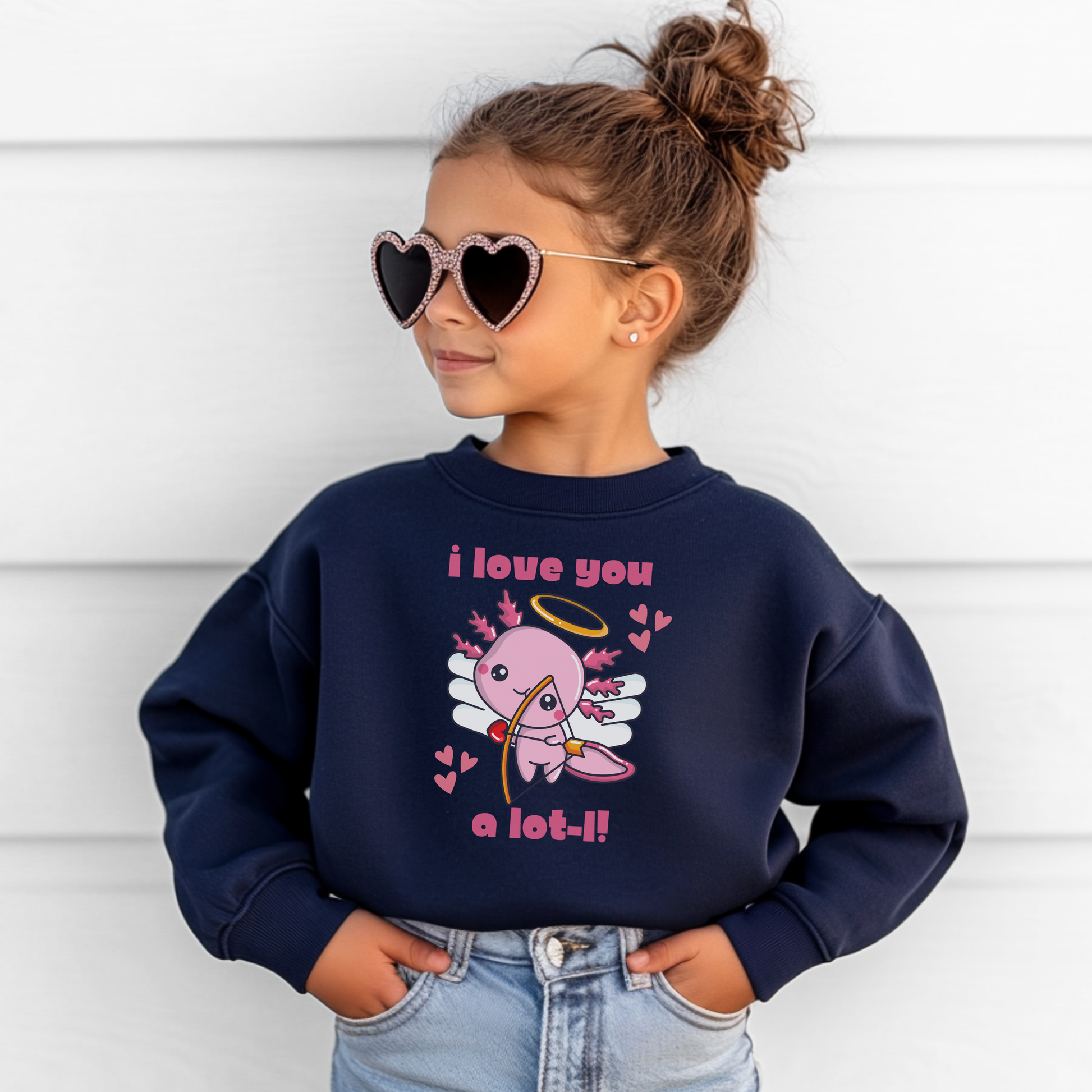 A young girl wearing a navy youth Valentine sweatshirt featuring a cute axolotl cupid design with wings, halo, hearts, and the phrase I love you a lot l. The classic crewneck fit offers cozy comfort for school days, Valentine classroom parties, and casual winter outfits. A fun and playful Valentine sweatshirt designed for kids who love animals, bright graphics, and festive seasonal clothing.