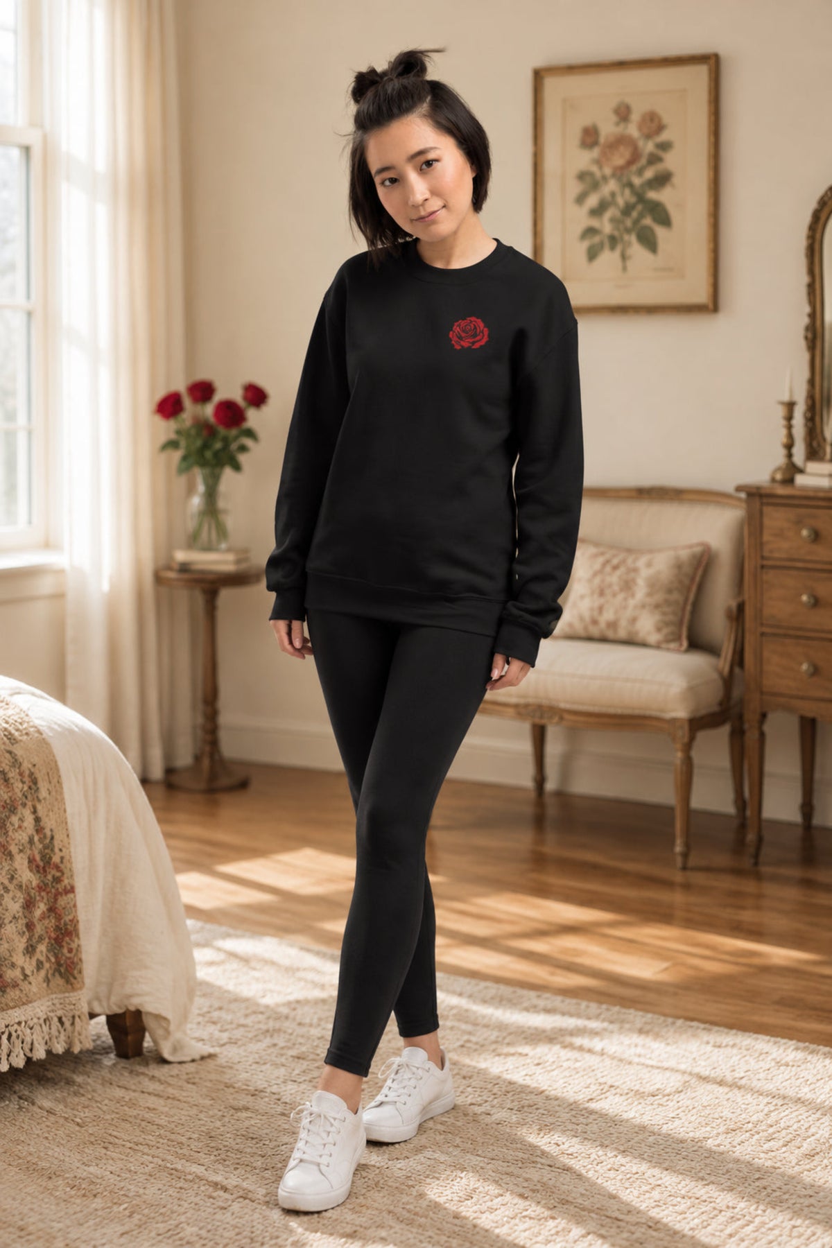 Woman modeling a black embroidered rose crewneck sweatshirt with a small red rose design on the left chest. Full view shows the classic crewneck shape, long sleeves, and relaxed fit. Red rose sweatshirt for women with a simple vintage floral look for casual outfits, birthdays, June birth flower gifts, and everyday wear.