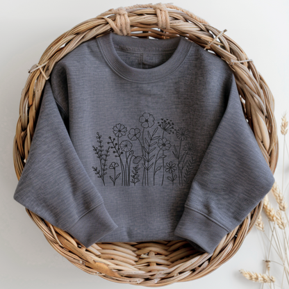 Image: A cozy dark grey sweatshirt with delicate black wildflower embroidery across the chest, showcasing a minimalist yet elegant botanical design. The soft fabric drapes effortlessly, offering comfort for everyday wear. This floral nature crewneck is perfect for layering, adding a subtle floral charm to casual outfits. A thoughtful gift for plant lovers or those who appreciate nature-inspired fashion, by jaecrece.