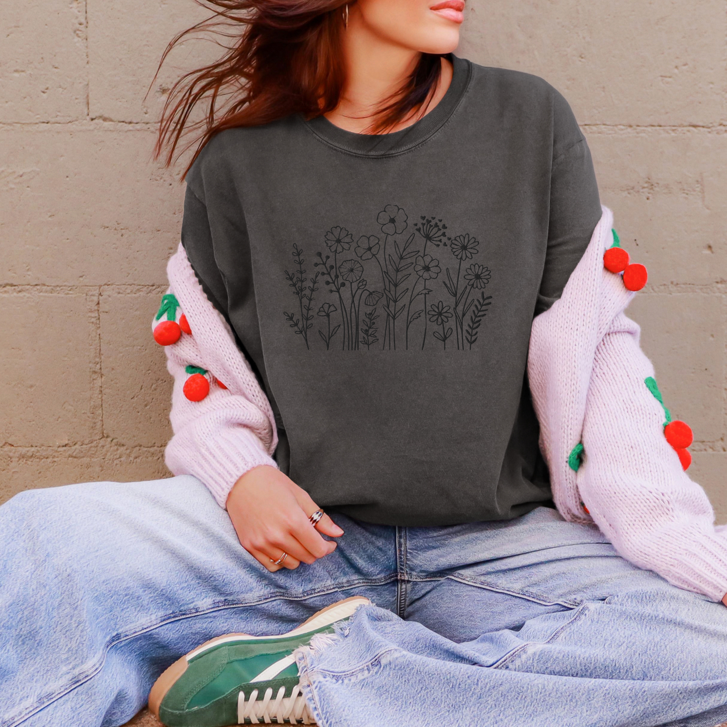 Image: A stylish dark grey crewneck shirt featuring black wildflower embroidery, blending a boho-chic aesthetic with classic casualwear. The floral pattern is stitched with precision, creating a subtle yet intricate nature-inspired motif. Whether paired with jeans or leggings, this embroidered sweater adds effortless charm to any wardrobe, making it an excellent gift for flower lovers and nature enthusiasts alike, by jaecrece.