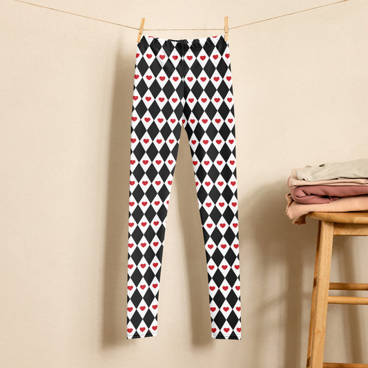 Image: Black and white harlequin check leggings with red heart accents. Available in sizes 2T-20 for toddlers, tween and teen girls. These yoga pants are designed for comfort and flexibility. Perfect for Halloween Queen of Hearts costumes. Also available in women's sizes for mommy and me matching outfits. 