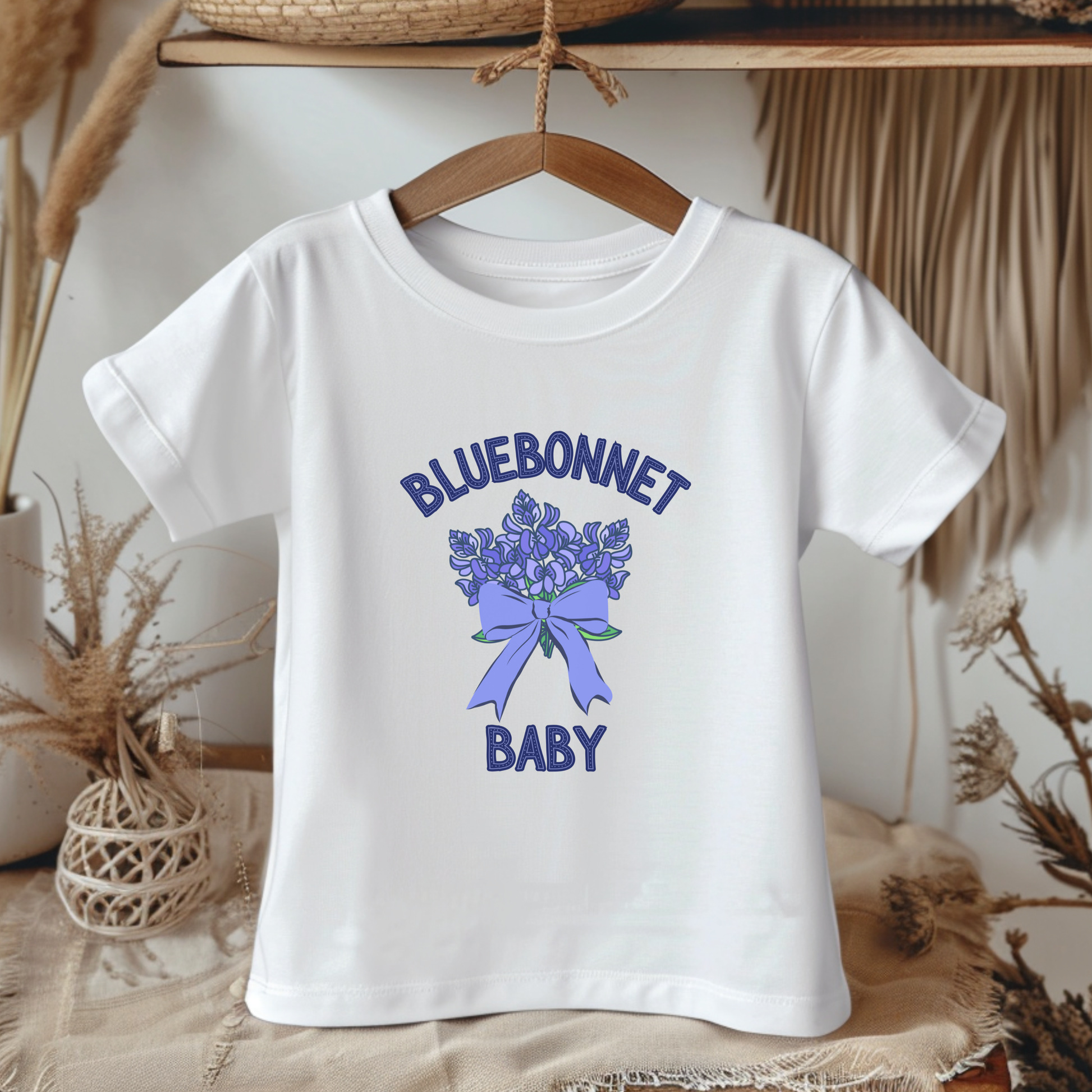 White t-shirt with bluebonnet design and text on a hanger against a neutral background