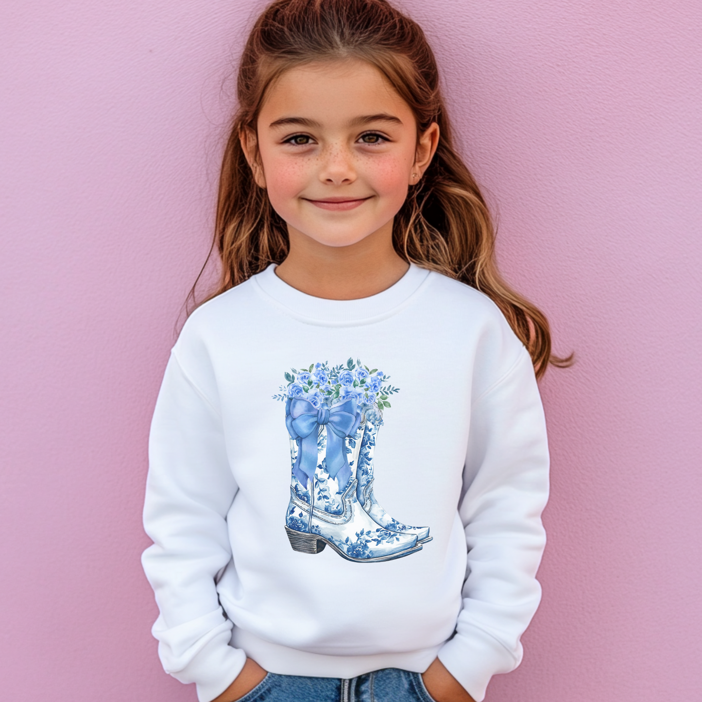 Image: Blue Toile Boots and Bows Sweatshirt in sizes for girls and toddlers. This pullover sweater features a pair of coastal cowgirl aesthetic cowboy boots with a blue bow and blue wildflowers. This country themed sweater makes a perfect gift for your daughter, by jaecrece