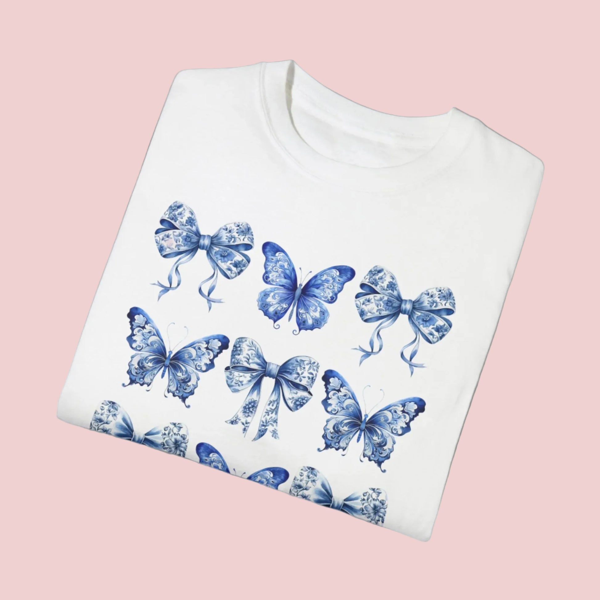 Image: With its dreamy butterfly and bow motif set against a vintage-inspired blue toile background, this women’s shirt blends soft girl style with French country elegance. A staple for bougie mamas and fans of the chinoiserie trend, it’s the perfect tee for family gatherings or spring strolls. Match it with girls’ and toddler sizes for an Instagram-ready mother-daughter look, by jaecrece.