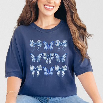 Image: A beautiful women’s tee with a vintage-inspired blue toile bow and butterfly design, ideal for fans of French aesthetic, chinoiserie, or soft girl fashion. This shirt flatters with cozy comfort and romantic vibes, perfectly aligned with coastal cowgirl style. A thoughtful piece for bougie mamas or matching family photoshoots, it coordinates with girls’ and toddler sizes for stylish mother-daughter outfits, by jaecrece.