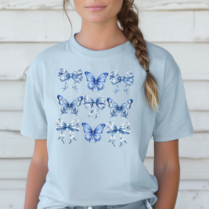 Image: This women’s shirt features a delicate blue toile bow print with butterflies and florals, inspired by classic French aesthetic and chinoiserie patterns. Perfect for those embracing the soft girl aesthetic, bougie mama style, or coastal cowgirl charm. Part of a family matching collection for coordinated outfits with toddlers and tweens, this tee is made for spring vibes and feminine flair, by jaecrece.