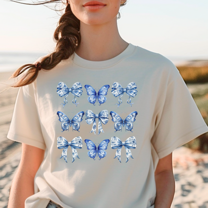 Image: Featuring a charming blue toile pattern with graceful butterflies and bows, this soft women’s shirt blends French countryside elegance with the trending soft girl aesthetic. Ideal for coastal cowgirl looks or stylish everyday wear, it’s a must-have for bougie mamas. Designed to match toddler and youth sizes, it’s part of our coordinated family collection and makes a beautiful gift for moms and daughters, by jaecrece.