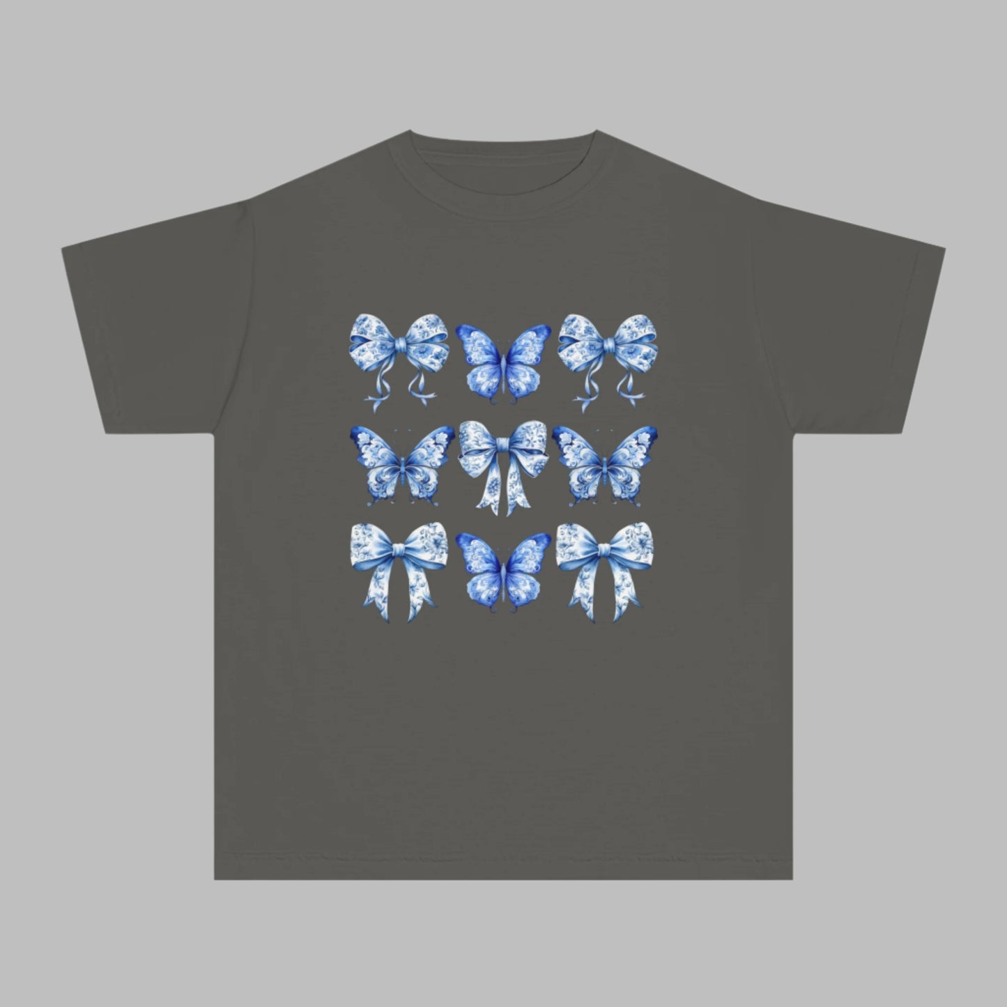 Image: Comfort Colors girls T-shirt featuring a soft vintage-inspired blue toile pattern of butterflies and bows, sized XS to XL. Ideal for tween girls who adore coquette trends, southern style, or coastal cowgirl fashion. This youth shirt in Chambray, White, Pepper, or True Navy is perfect for holidays, back to school, or photo ops. Also available in toddler and women’s sizes for stylish matching moments, by jaecrece.

