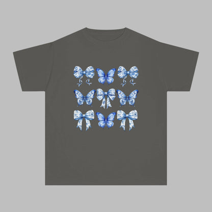 Image: Comfort Colors girls T-shirt featuring a soft vintage-inspired blue toile pattern of butterflies and bows, sized XS to XL. Ideal for tween girls who adore coquette trends, southern style, or coastal cowgirl fashion. This youth shirt in Chambray, White, Pepper, or True Navy is perfect for holidays, back to school, or photo ops. Also available in toddler and women’s sizes for stylish matching moments, by jaecrece.

