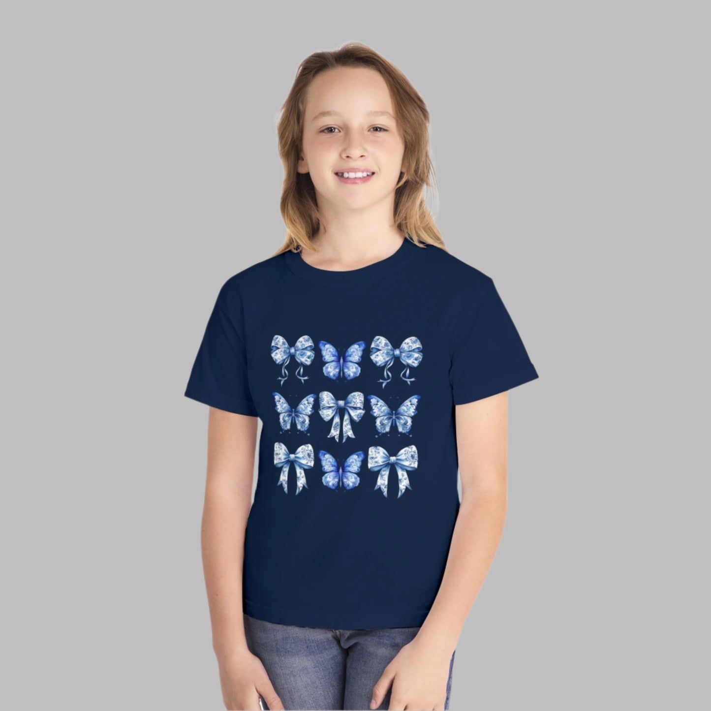 Image: Girls Comfort Colors T-shirt in blue toile print with butterflies and bows, inspired by Texas coquette and soft girl style. This sweet youth tee is perfect for everyday wear, school, or travel. Sized XS through XL in Chambray, White, True Navy, and Pepper. Coordinating styles for toddlers and women available in shop, ideal for family photos, festivals, or gifting, by jaecrece.
