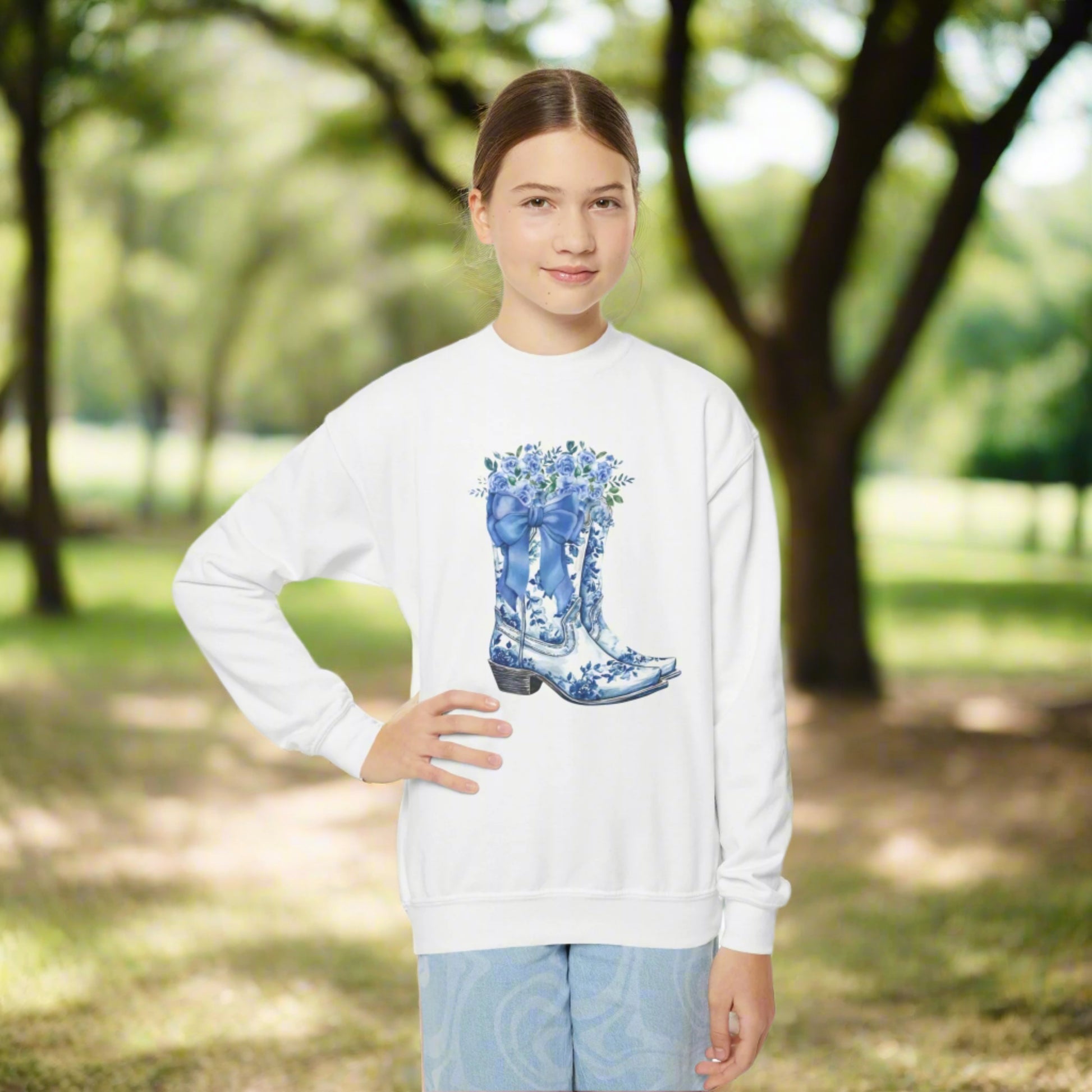 Image: Blue Toile Boots and Bows Sweatshirt in sizes for girls and toddlers. This pullover sweater features a pair of coastal cowgirl aesthetic cowboy boots with a blue bow and blue wildflowers. This country themed sweater makes a perfect gift for your daughter,  by jaecrece