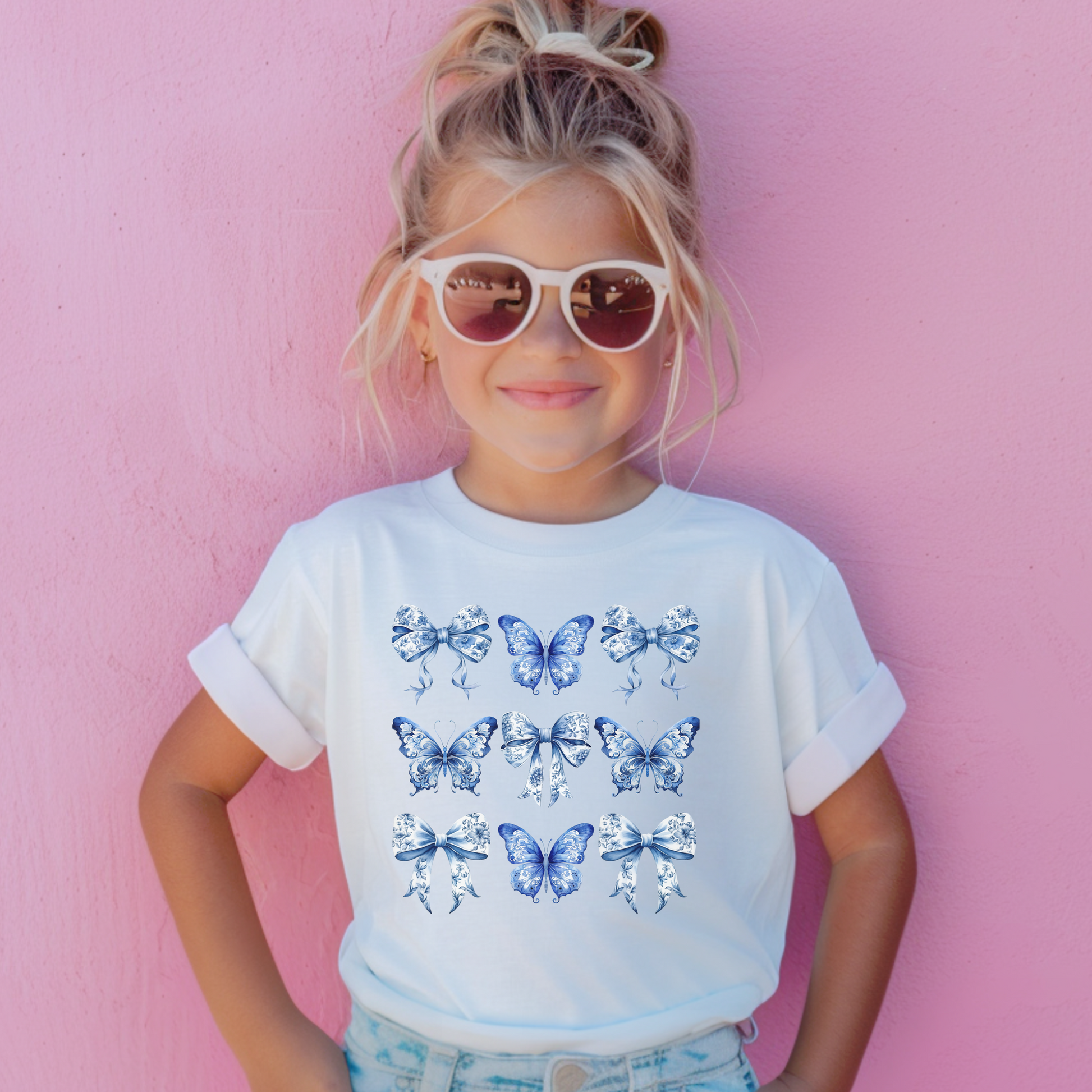 Image: A youth girls’ T-shirt that captures the heart of southern charm and vintage design, this Comfort Colors tee features a toile print of butterflies and bows in soft blue. Sized XS to XL and available in Chambray, White, True Navy, and Pepper, it is a perfect mix of Texas coquette and modern comfort. Match with coordinating family pieces for a full look, by jaecrece.