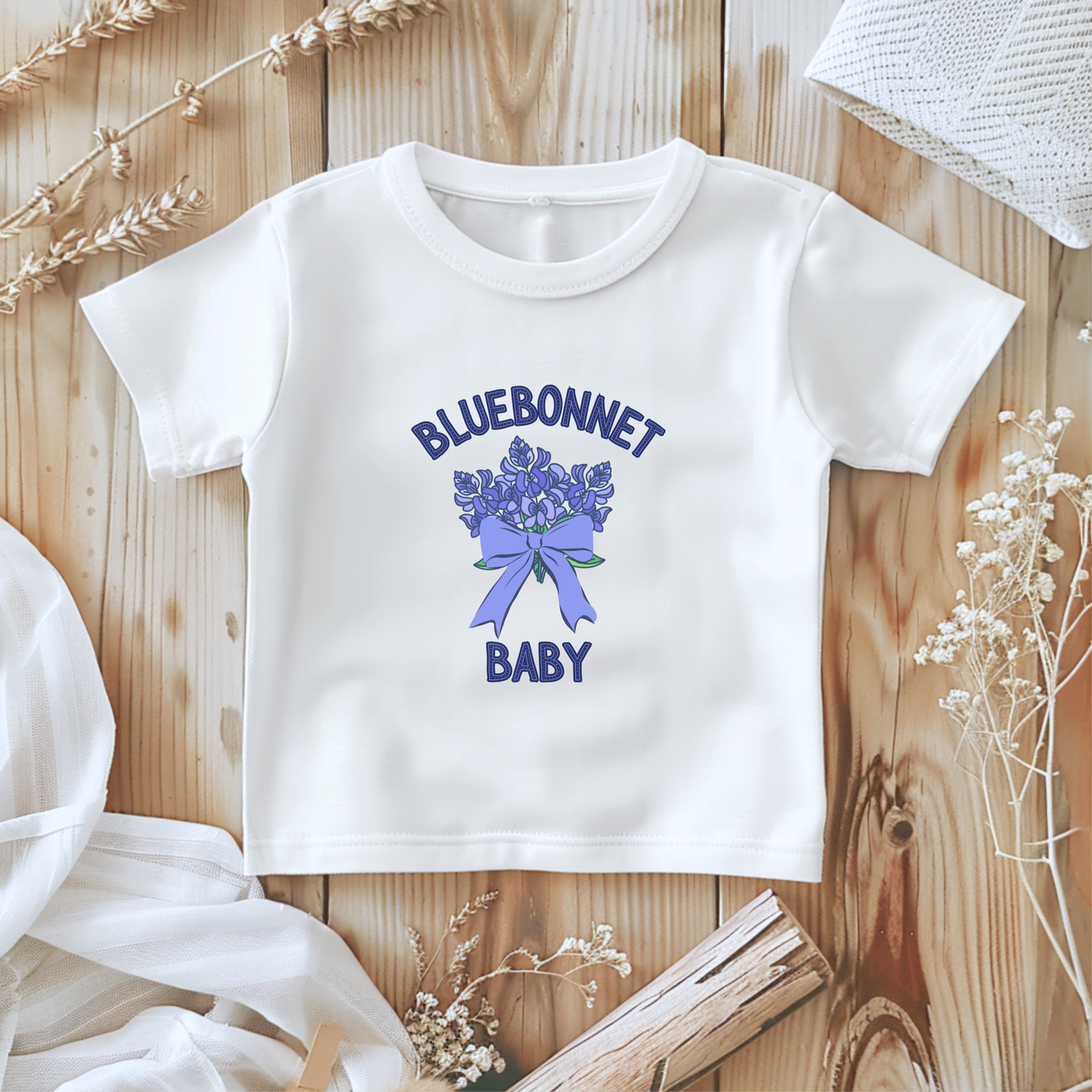 Soft Bella+Canvas 100B Bluebonnet Baby T-Shirt displayed flat, featuring a watercolor bluebonnet design inspired by the Texas state flower. This lightweight cotton baby tee, available in White and Athletic Heather, makes a sweet Texas wildflower baby gift. Perfect for newborns to 24 months, this southern-inspired baby shirt blends comfort and charm for everyday wear or springtime photos.