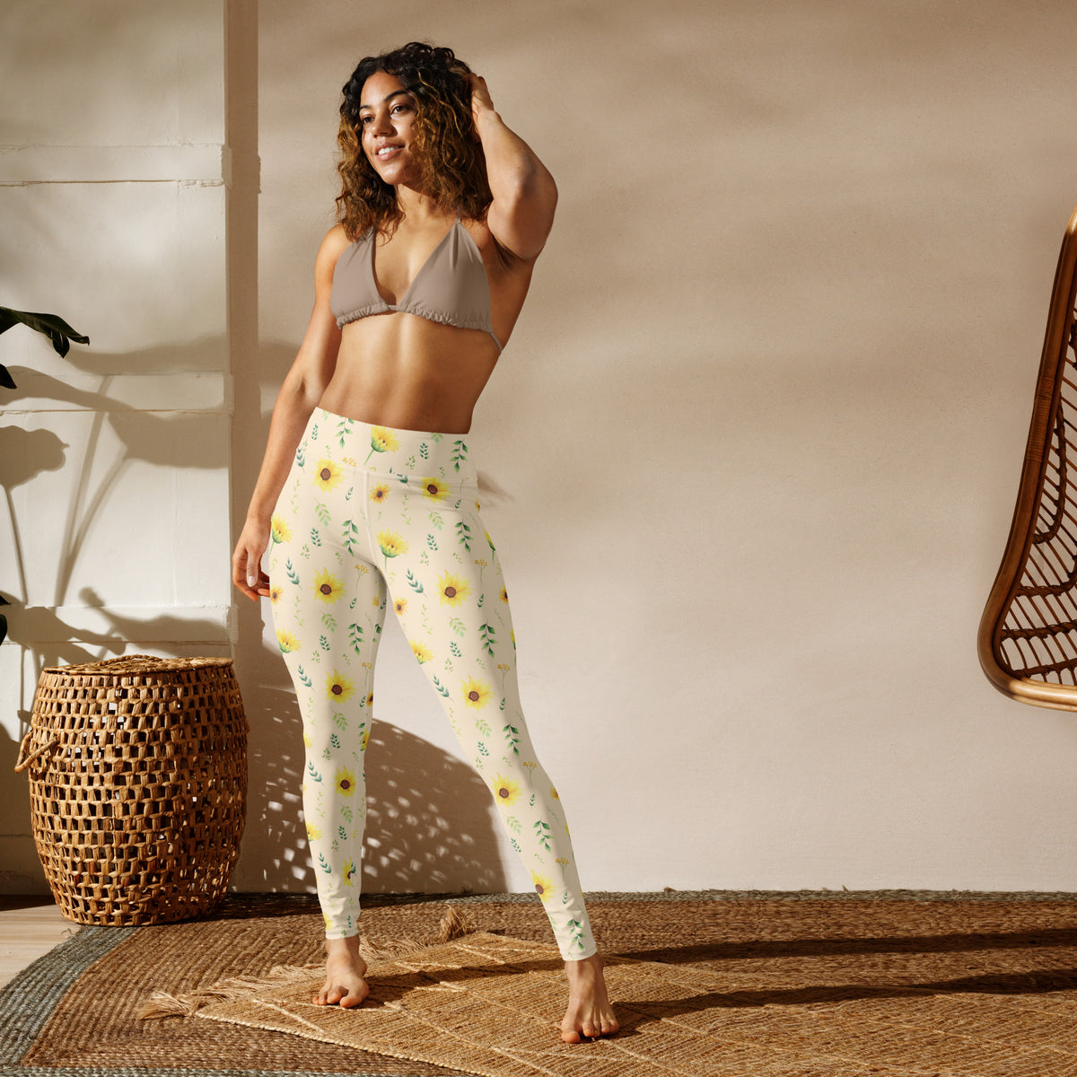 Women's yoga leggings featuring a delicate botanical print of yellow sunflowers, green foliage, and small leafy branches on a cream background. The smooth fabric has four way stretch for comfortable movement, while the high rise waistband provides comfortable coverage. The garden inspired design makes these leggings versatile enough for yoga and walking as well as casual outfits, errands, travel, and relaxing days at home.