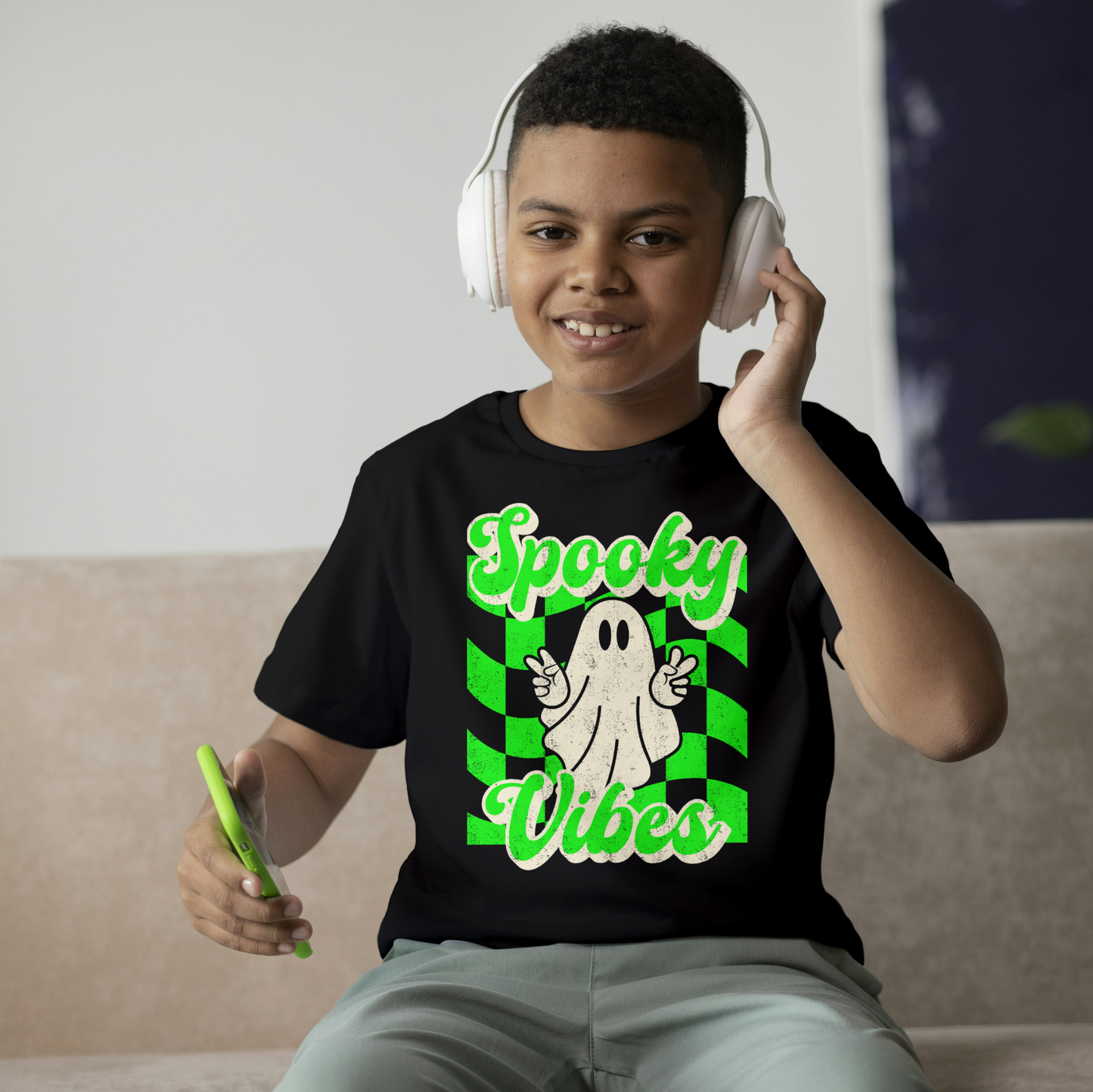 Black Spooky Vibes Child Shirt with a bright green checkerboard pattern and a cute ghost showing the peace sign. The text reads Spooky Vibes. This Halloween tee is perfect for girls and boys! By jaecrece